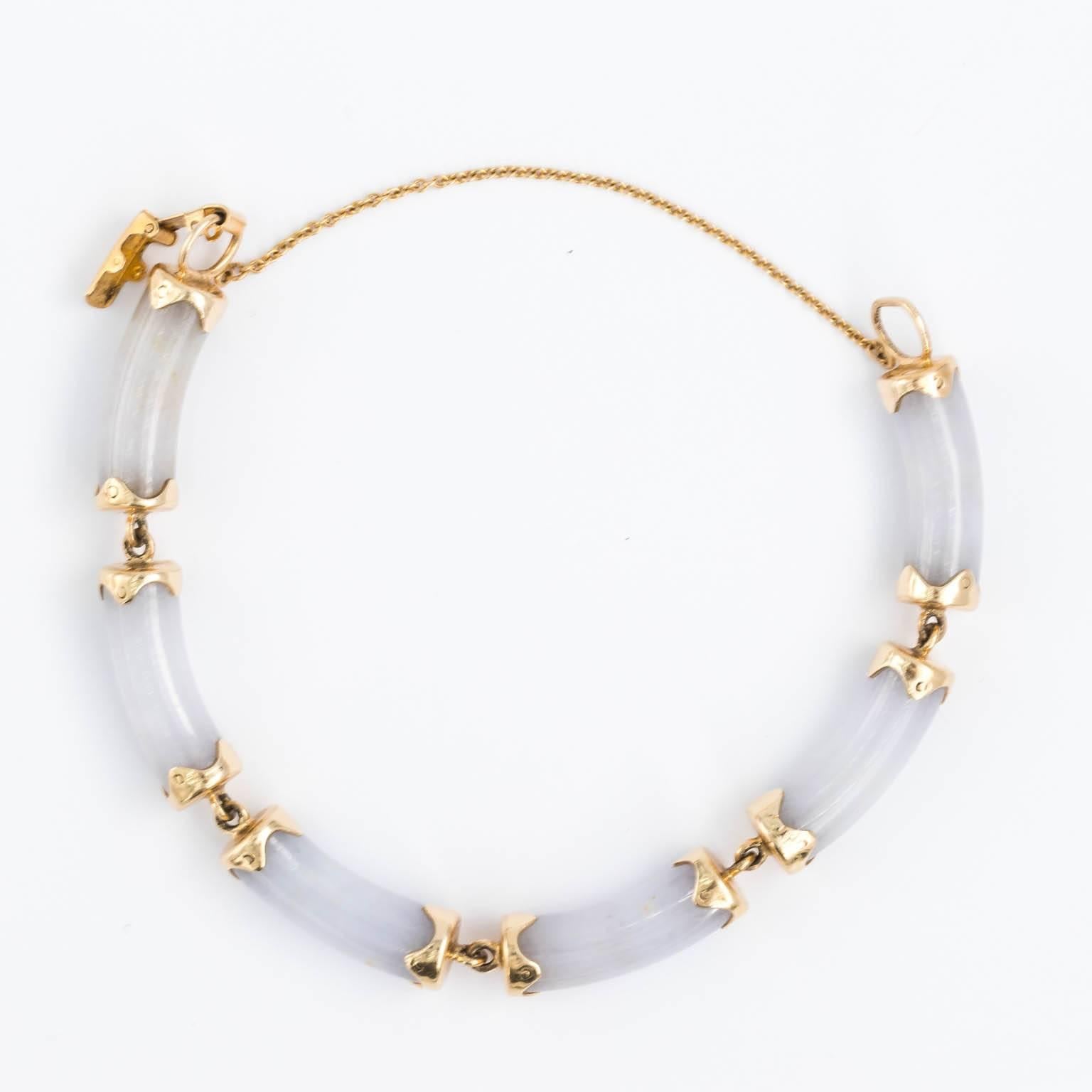 Circa 1970s piece of jewelry from Ming's of Honolulu. It is a sectional bracelet made from 6 pieces of cylindrical jade of over Ian inch long, 8 mm thick. Each piece is capped in a flower pedal shaped constructed from solid 14k gold, and finished