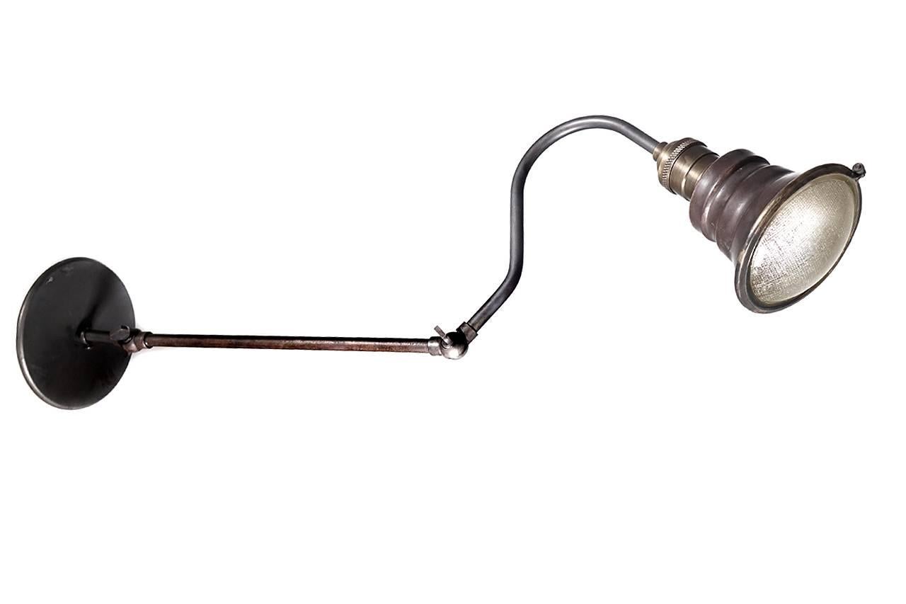This brass and copper lamp is articulated at two points and extends 22 inches from the wall. The interior of the spots are silvered and a brass ring holds a textured 3.75 inch glass lens. These are perfect bedside readings lamps. Both the brass and
