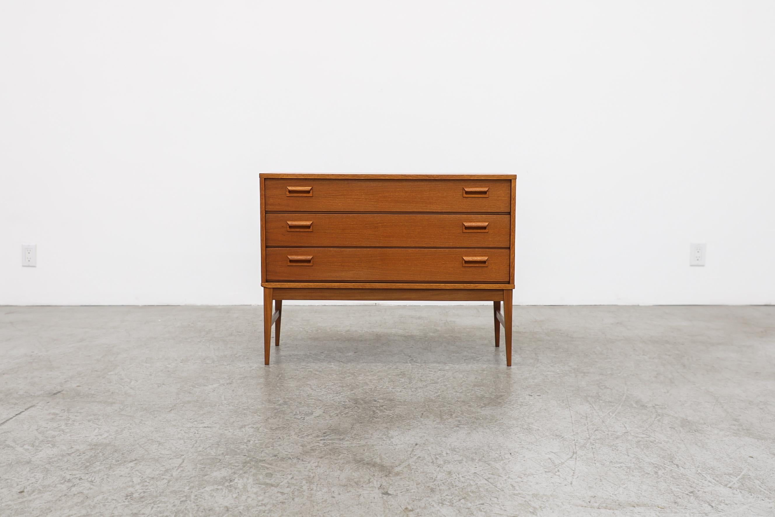 This Mid-Century Danish teak mini dresser or nightstand has 3 drawers with horizontal handles. In original condition with visible wear, consistent with its age and use.