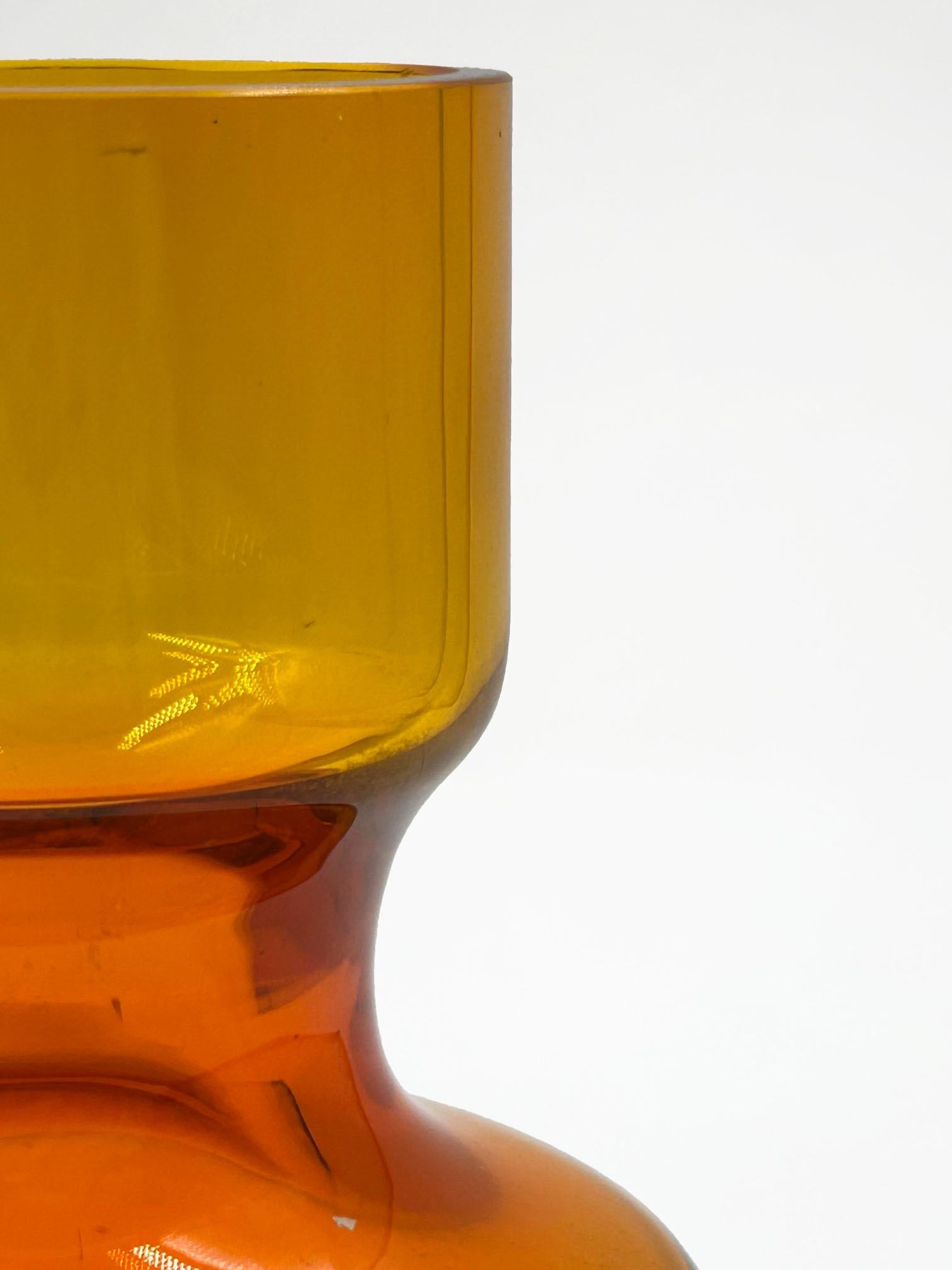 Finnische Mini-Glasvase von Tapio Wirkkala
Diese Mini-Vase aus finnischem Glas, entworfen von Tapio Wirkkala, ist bernsteinfarben und hat einen subtilen Verlauf zu einem helleren, fast gelblichen Farbton an der Spitze. Das Design zeichnet sich durch