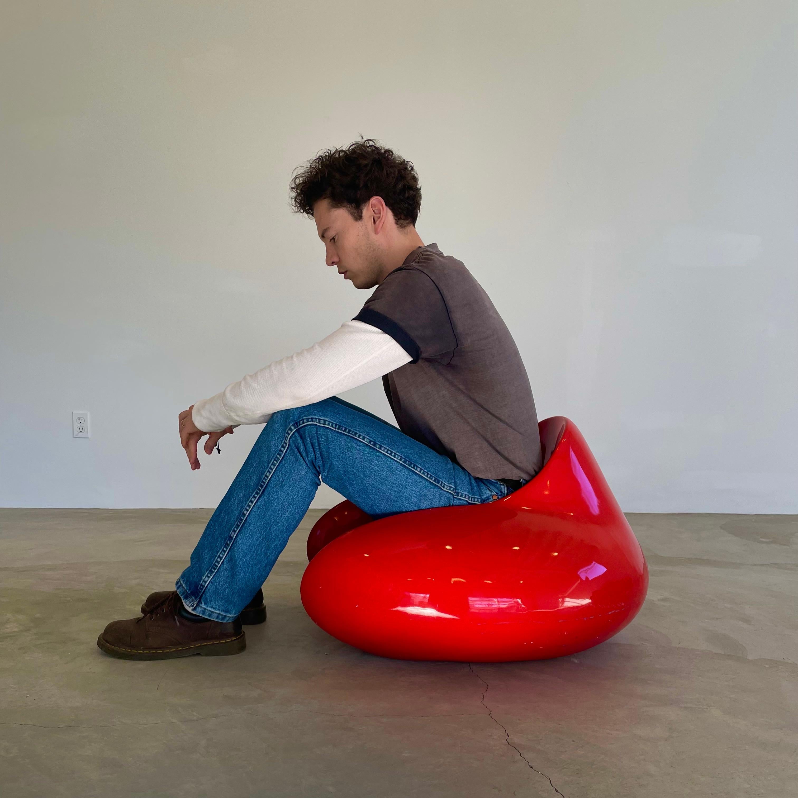 Unique fiberglass chair in the style of Eero Aarnio's Formula chair. Handmade and finished in candy apple red. Smooth lines and curves that shoot up forming a backrest and settle back seamlessly into the armrests. The seat rests low to the ground