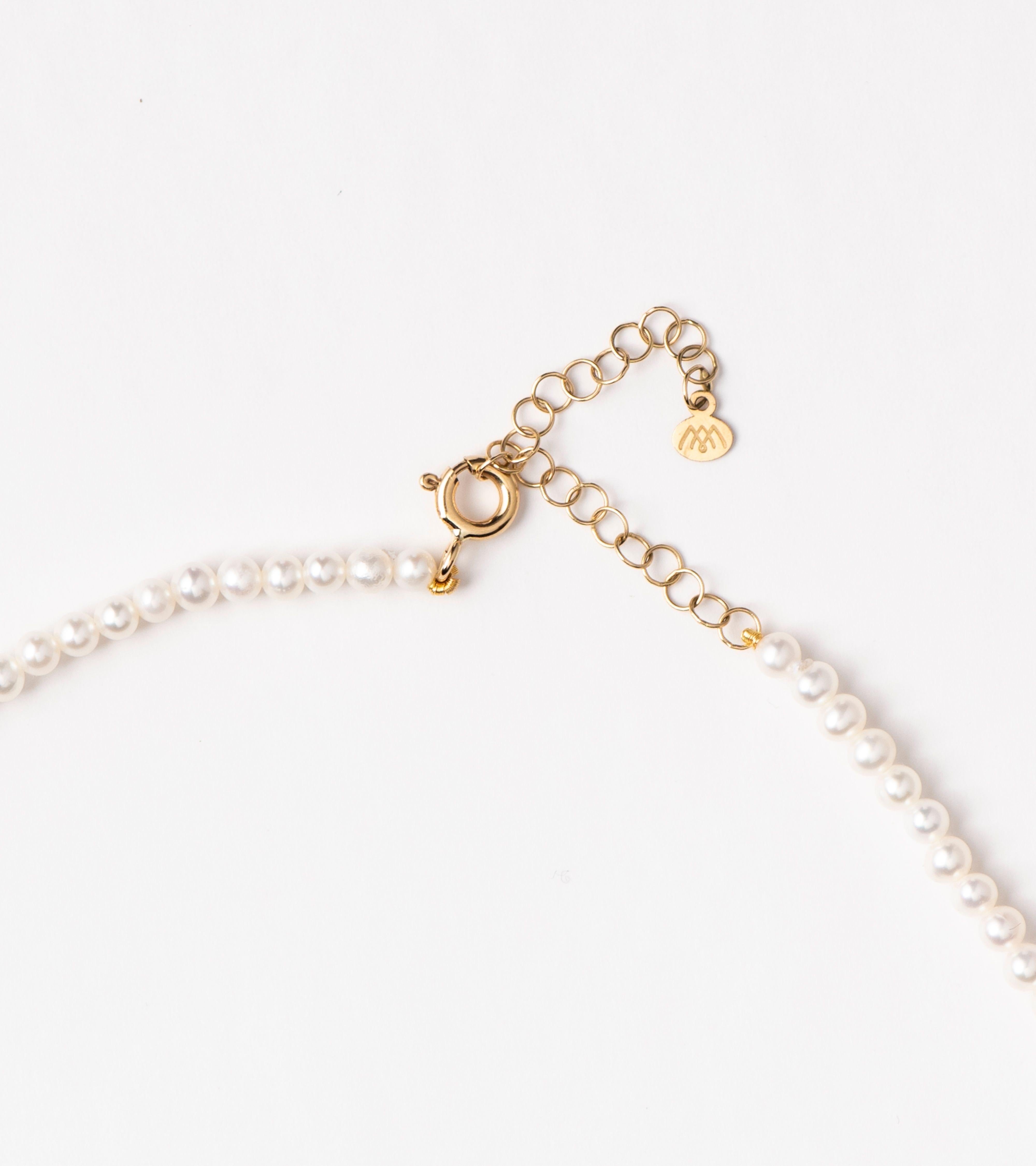 Unsere Halskette mit Barock-Charme an Mini-Perlen zeichnet sich durch eine barocke, tropfenförmige Perle aus, die an einem Strang mit Mini-Süßwasserperlen aufgehängt ist und von schimmernden Diamanten an ihrem Haken akzentuiert wird. Die zeitlose