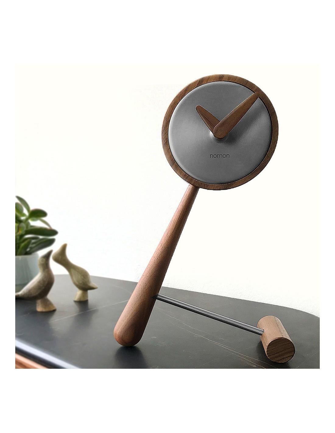 It is made with the greatest precision to represent a high-end designer clock made to turn the desktop into a true showcase where it can be seen by everyone. 
Mini Puntero T table clock : Box in graphite finished brass, hands and body in