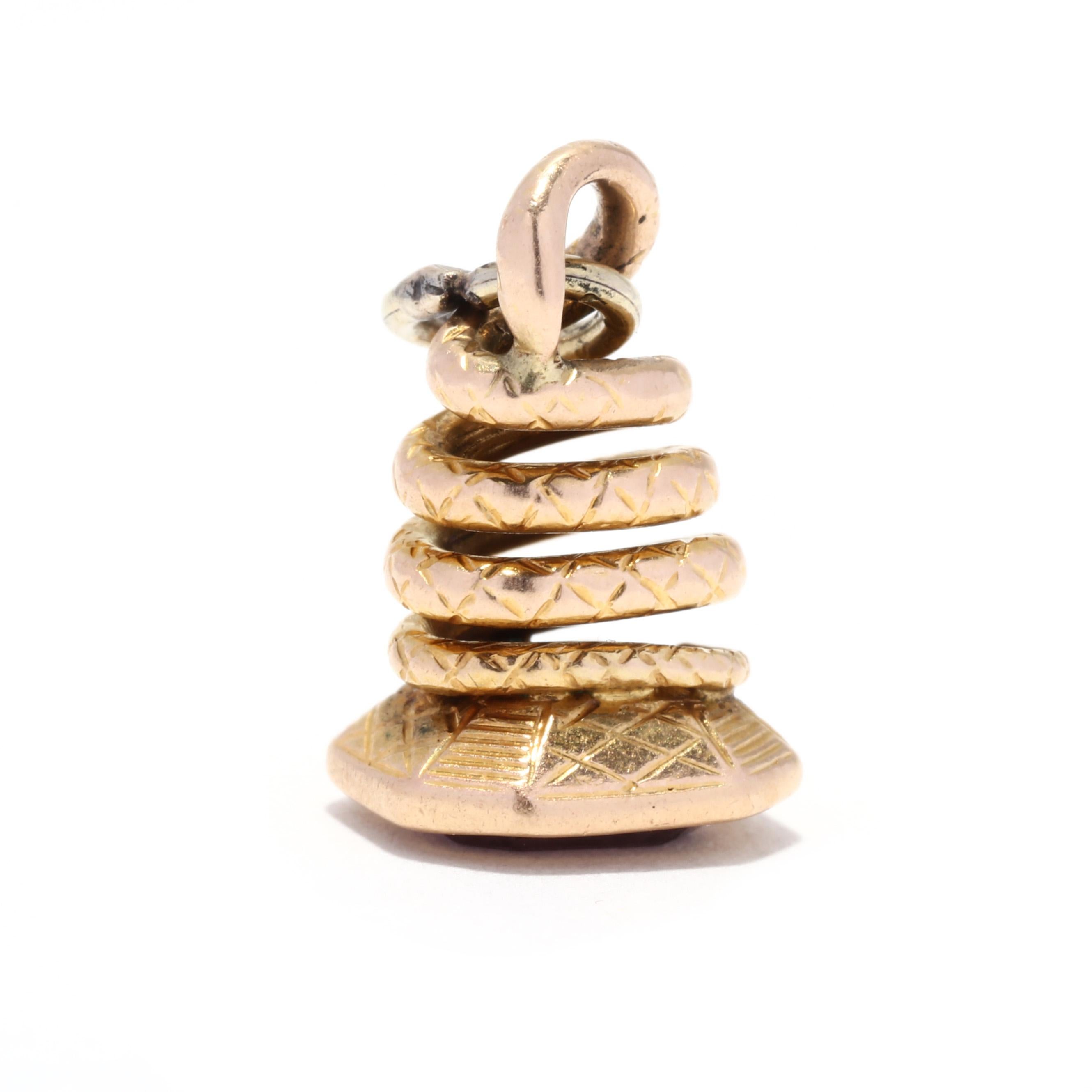 A victorian 14 karat yellow gold snake watch fob charm. This miniature charm features a textured coiled snake motif, sitting atop a rectangular base with a bezel set purple foil back quartz stone.

Length: 5/8 in.

Width: 5/16 in.

Weight: 1.4