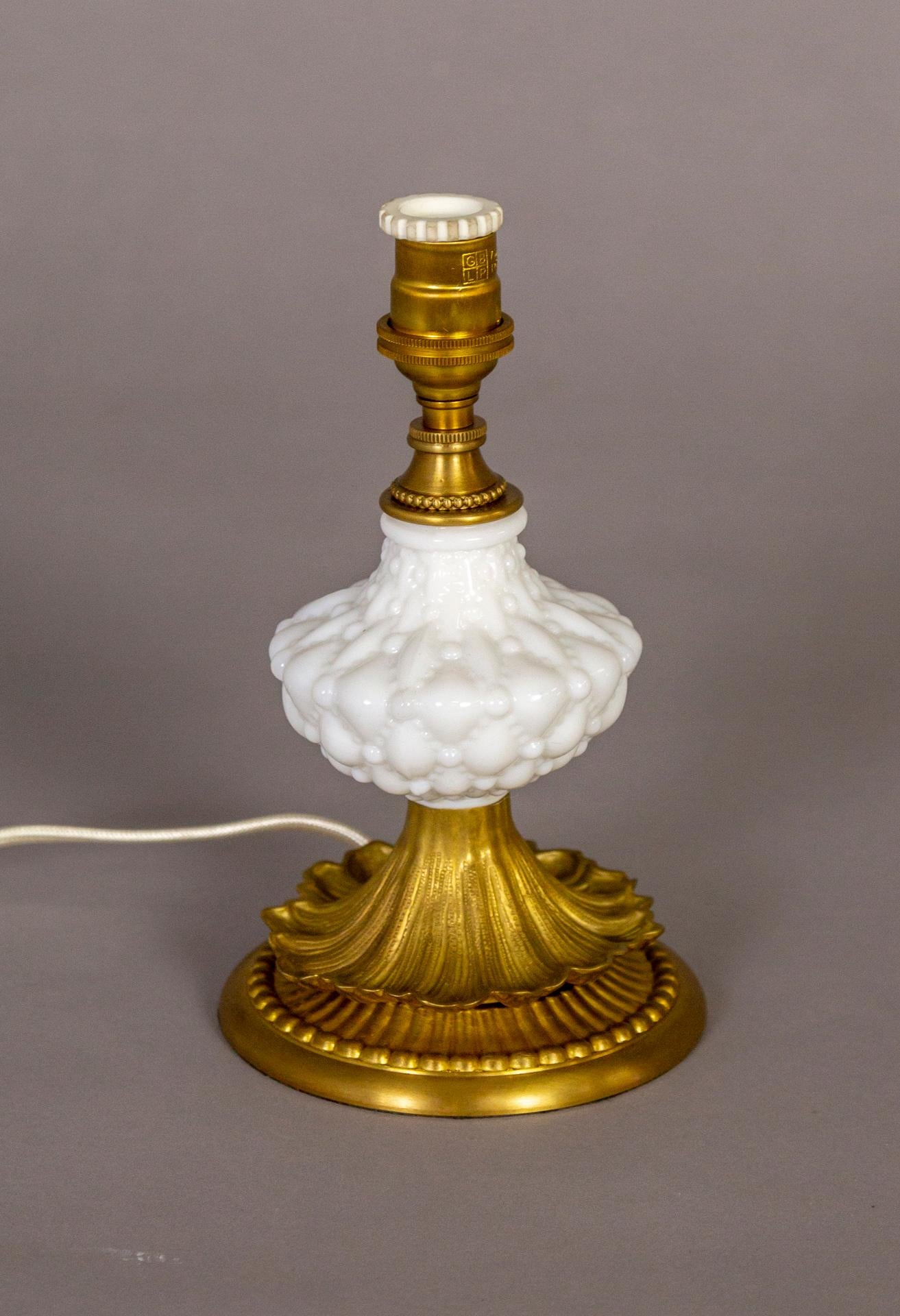 A petite, vintage, desk or dressing table lamp in white hobnail glass and detailed brass design. With an ivory color silk, empire bell shape, clip-on shade. Circa 1940s. In-line switch; candelabra socket. Newly wired. Measures: 12.5