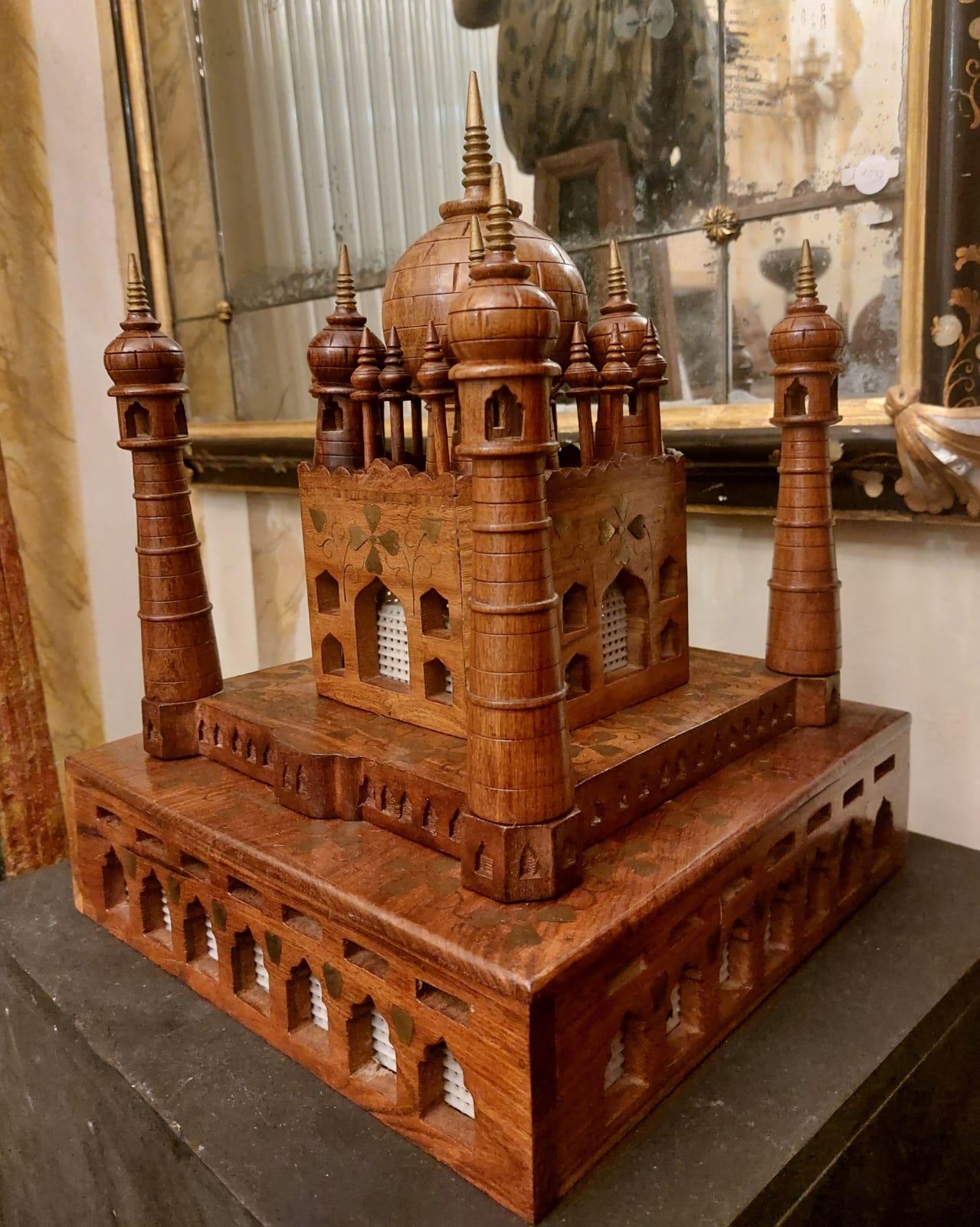La figurine est fabriquée dans un bois similaire au noyer, plus probablement un palissandre asiatique. La surface est décorée de motifs floraux qui seraient incrustés dans un alliage métallique. Les extrémités de la construction sont dorées.
A