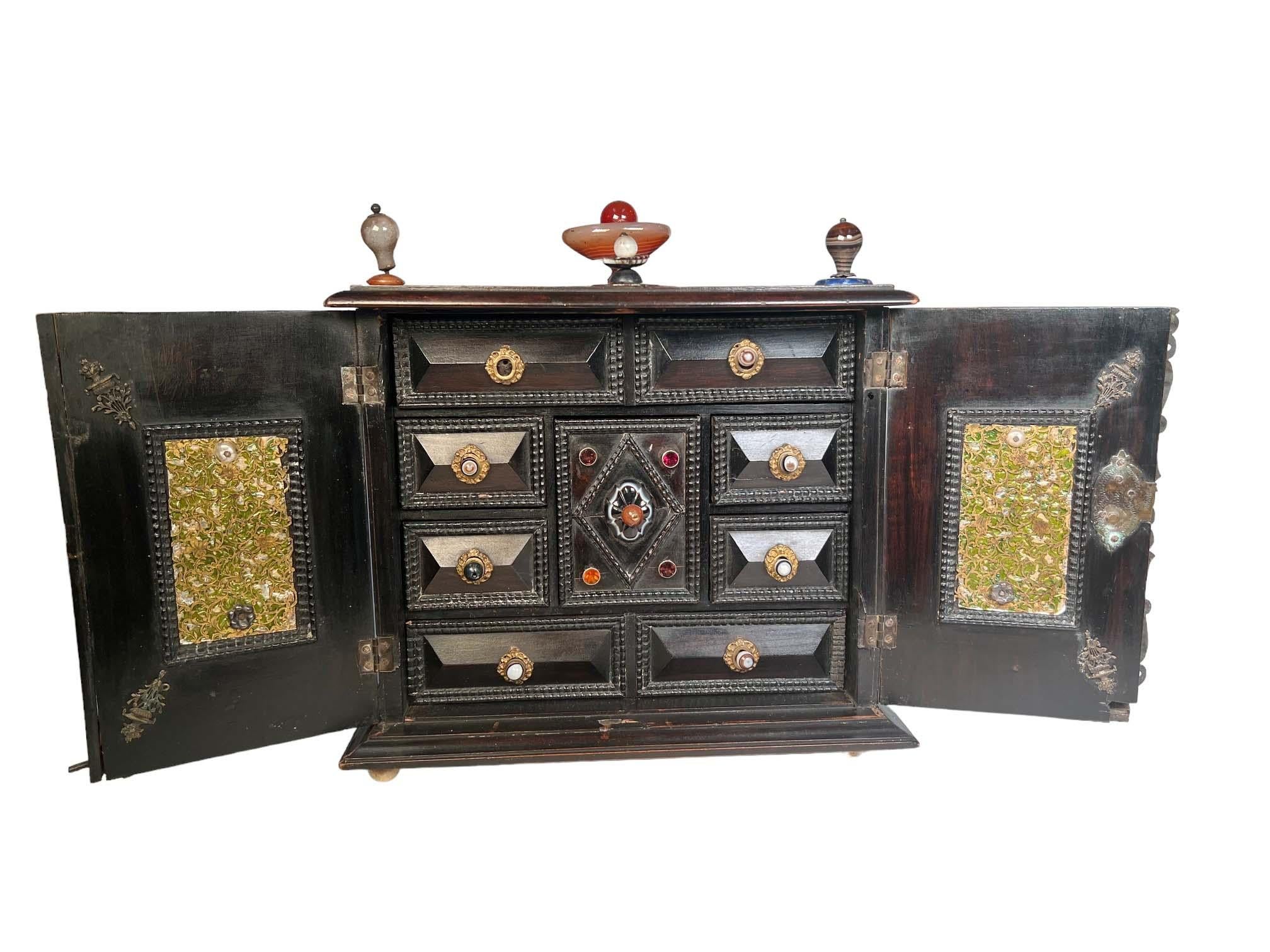 Armoire italienne en bois sculpté et métal avec pierres semi-précieuses. Deux portes s'ouvrent sur des tiroirs avec des pierres semi-précieuses montées sur chaque tiroir. Vers 1780-1820.
