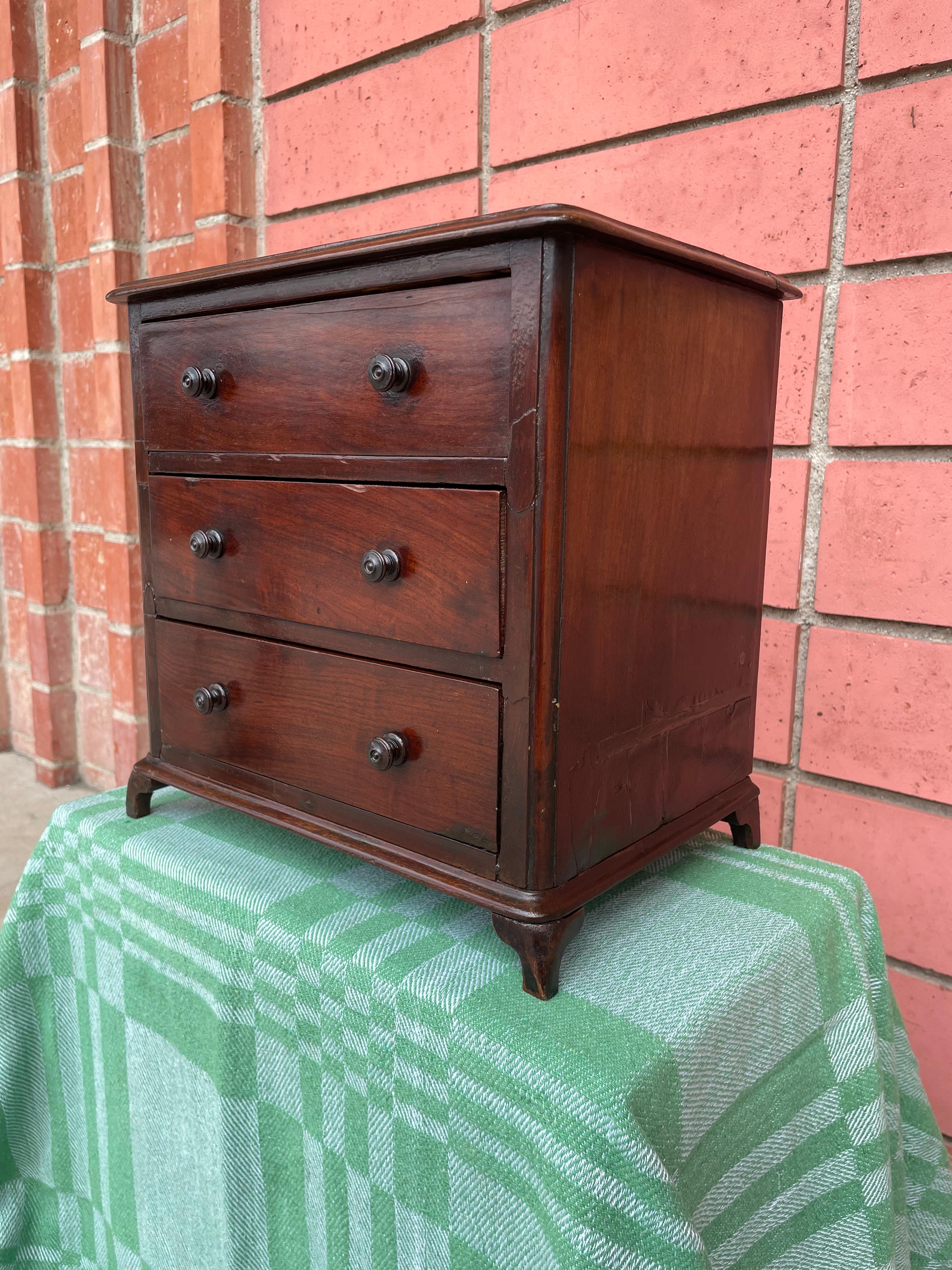 This early 19th century Georgian Miniature Chest of Drawers would have been constructed by the workshop to show potential clients examples of their products. Made from sturdy mahogany wood, raised on small detailed braket feet, and hand