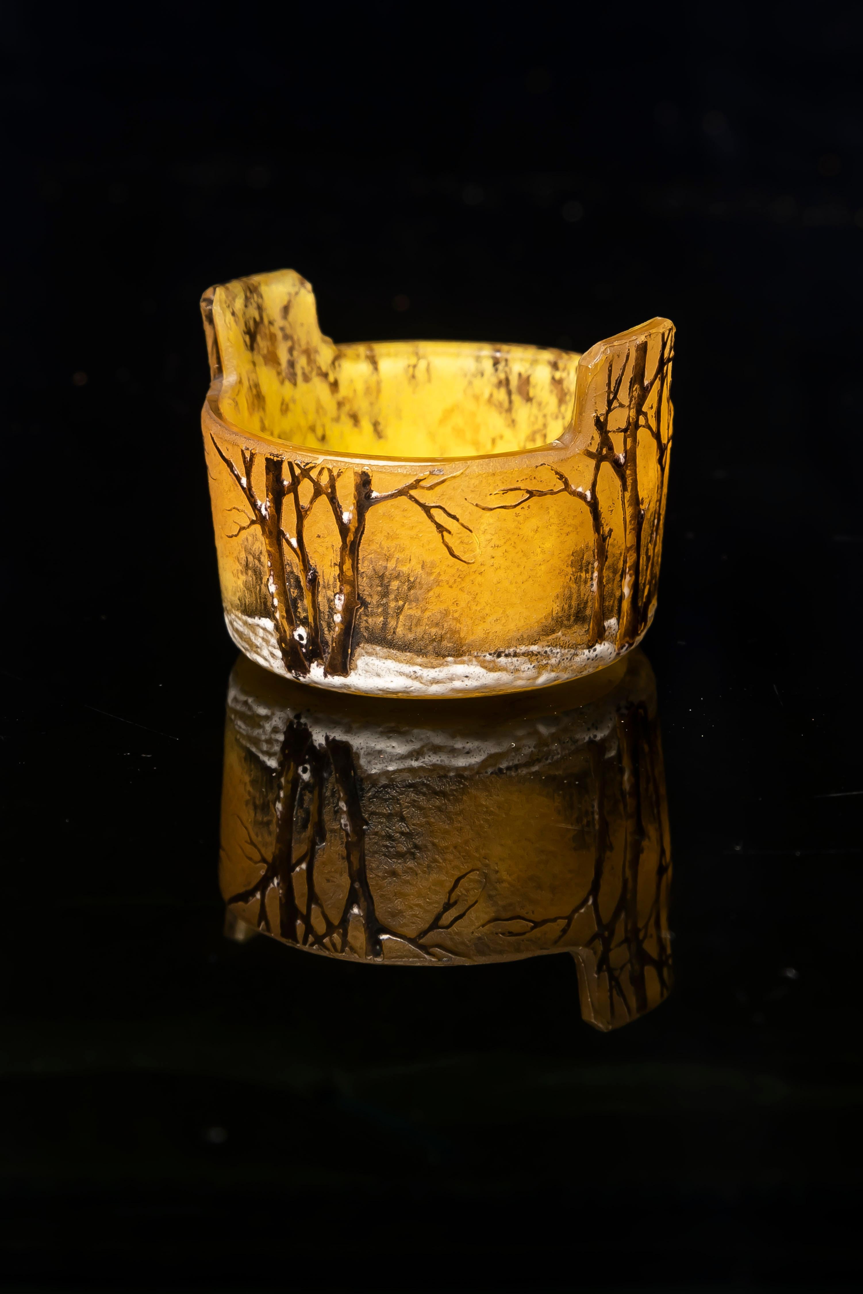 Squisito vaso in miniatura in vetro acidato e smaltato, firmato Daum Nancy con la croce di Lorrain. Prodotto in Francia all'inizio del XX secolo, questo pezzo finemente lavorato cattura l'atmosfera poetica dei paesaggi invernali, un motivo