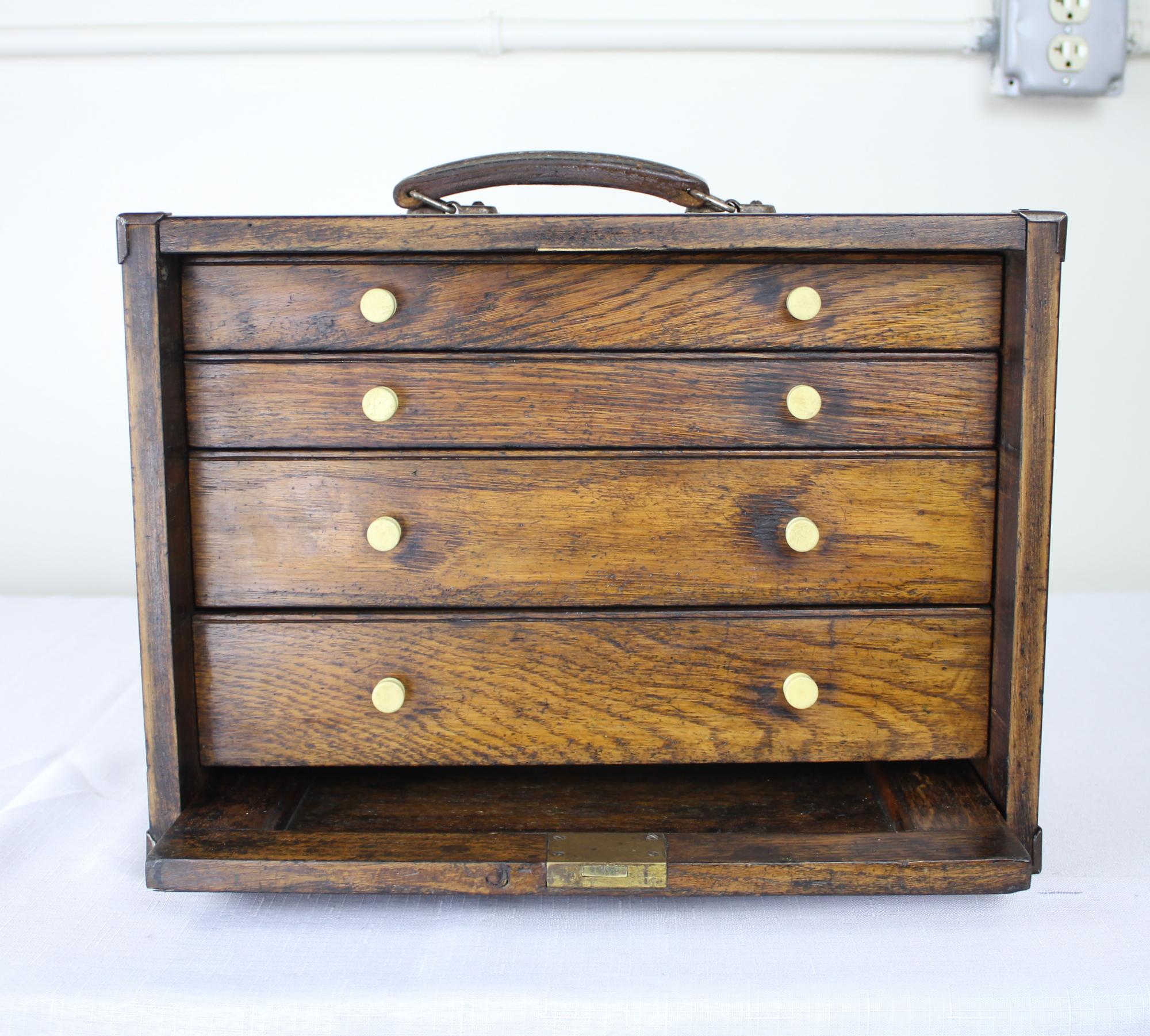 A miniature English oak Campaign chest of drawers with working key. Most likely used by politicians and business men on the road. We love the pull out / pull-out door and bakelite drawer knobs. Good visible dovetailing at the corners. Very
