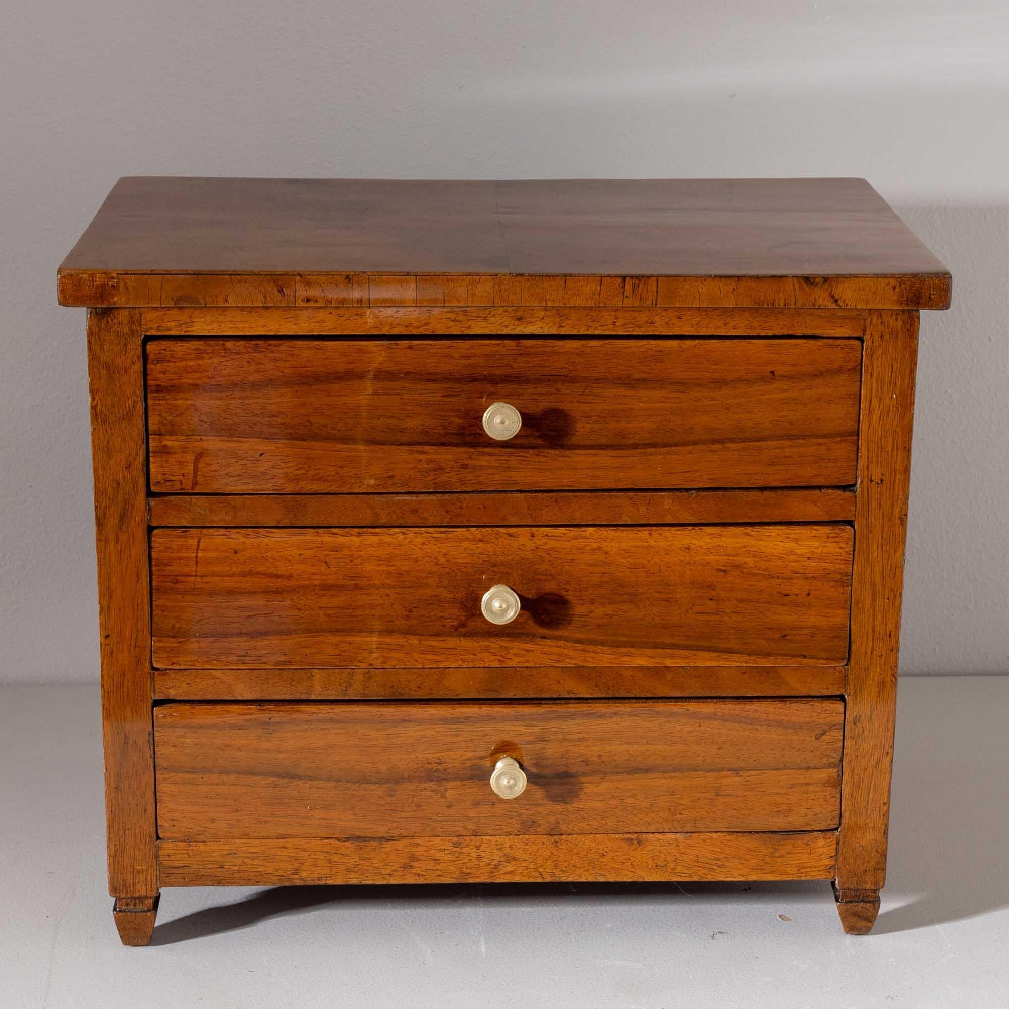 Miniature chest of drawers made of walnut with small square pointed feet and brass knobs. The chest of drawers was restored and polished by hand.