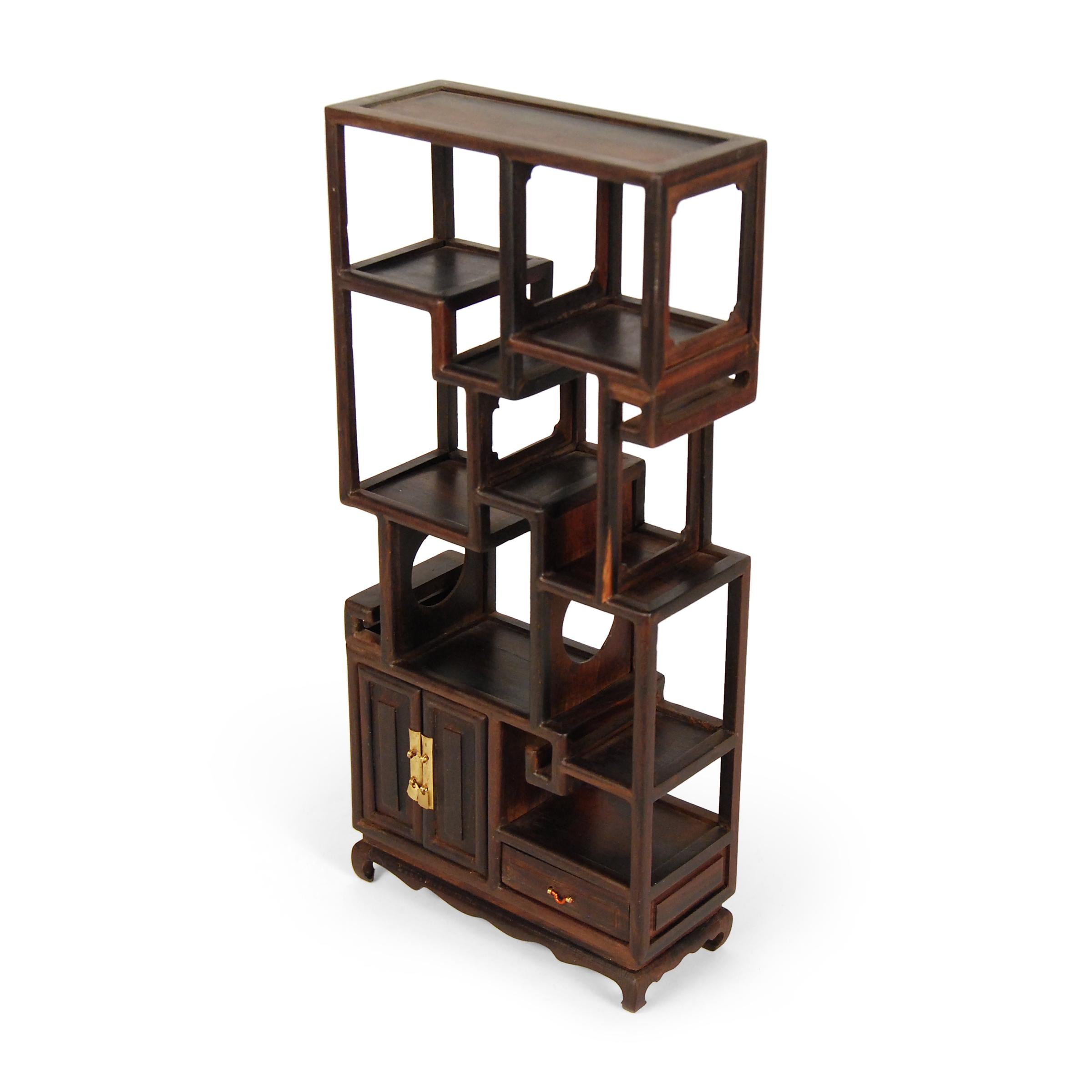 A full size bookcase with this level of workmanship and detail would be an incredible find, but this beautiful piece of furniture—at only ten inches tall—is perfectly constructed down to the tiniest minutia. Crafted of a dark hardwood, the small