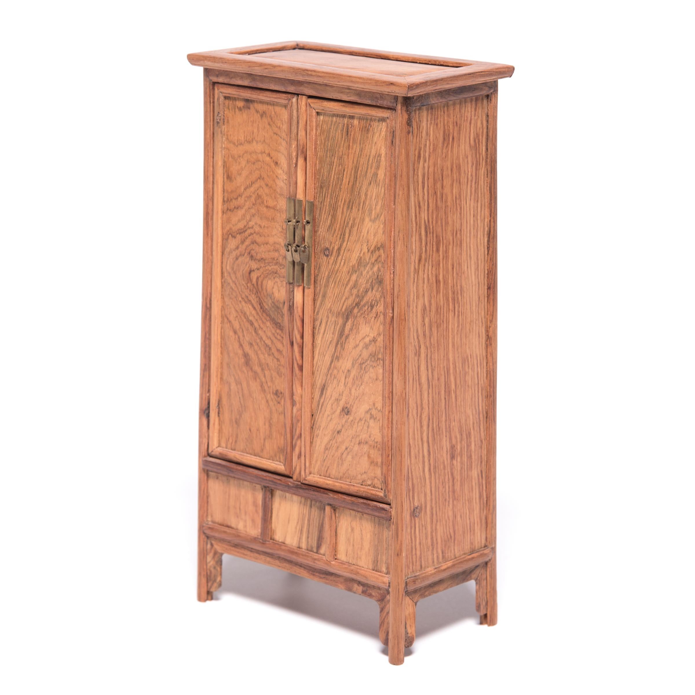 A full size cabinet with this level of workmanship would be an incredible find, but this beautiful piece of furniture, at only nine inches tall, is perfectly constructed down to the tiniest minutia. The petite cabinet was made in northern China out