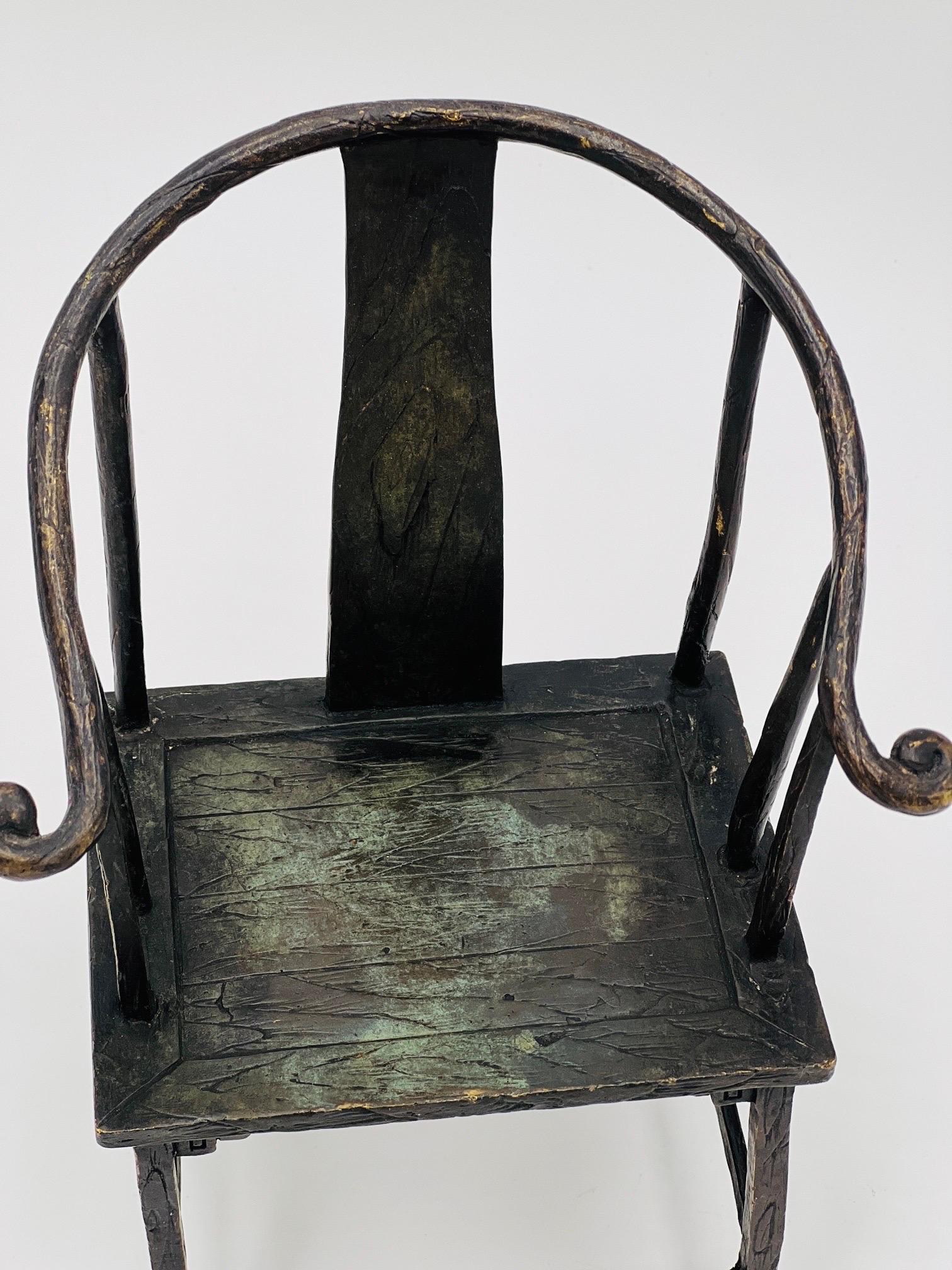 A contemporary bronze sculpture of a Chinese horseshoe chair constructed in bronze with patina to surface. Marked on back of frame “Milo - 2010”. 

Measures: 8.375” H X 6.25” W X 3.875” D.