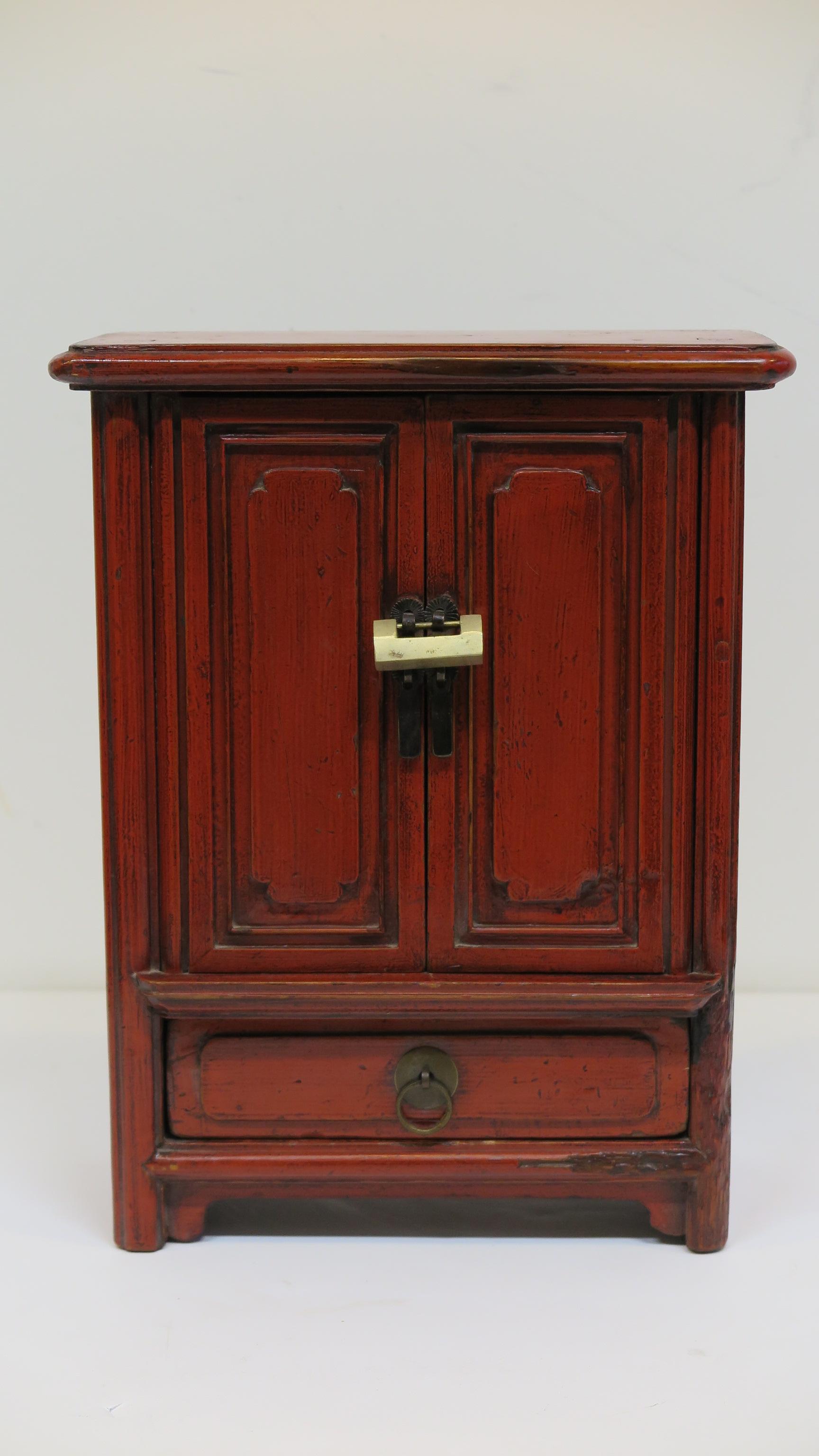 Miniature antique Chinese red lacquer panel cabinet Qing dynasty. Miniature Chinese panel cabinet with traditional brass hanging lock. Carved panel doors also having the left side of the cabinet with panel and the right side panel has wear pictured.