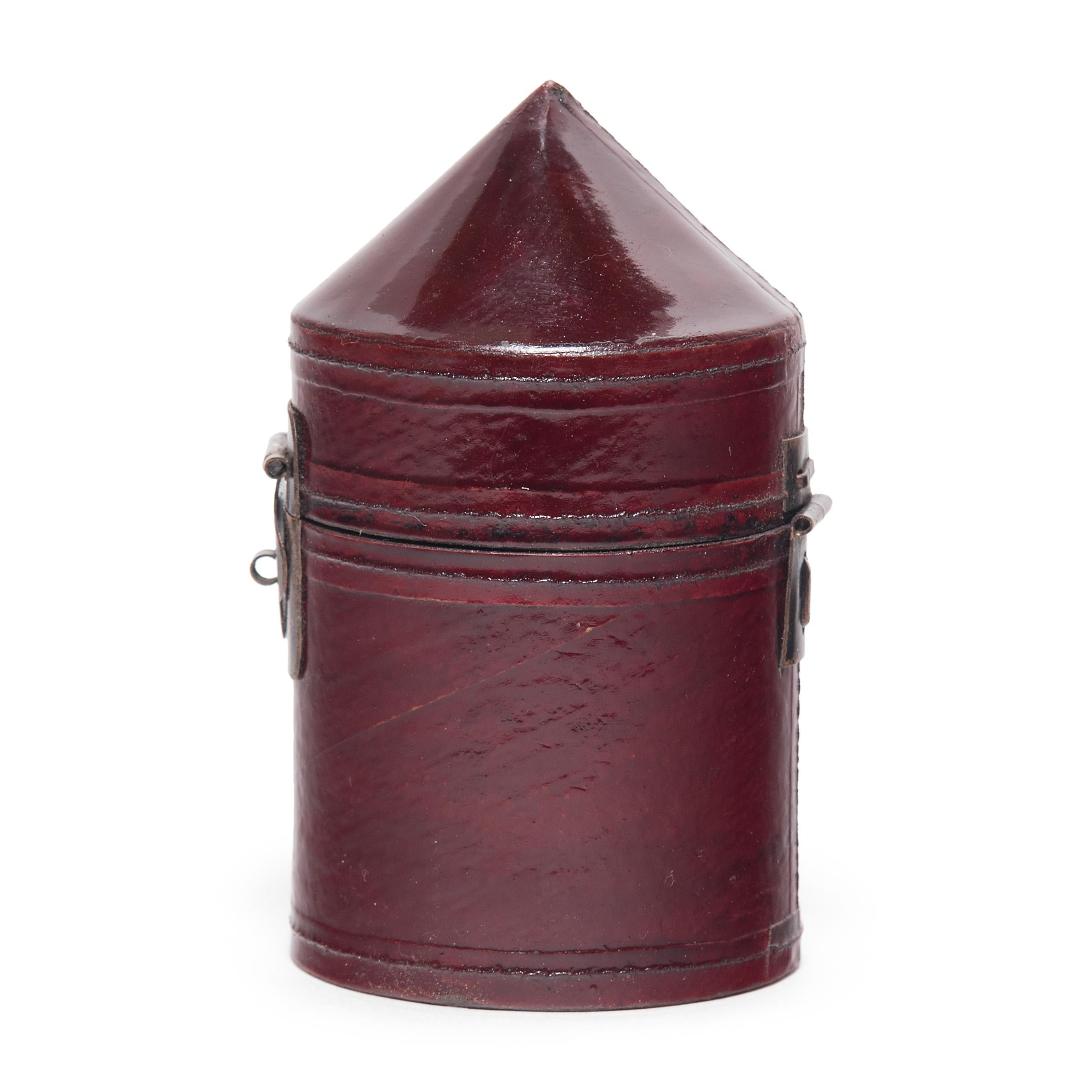 This petite cylindrical box is a miniature version of a Qing-dynasty official's hat box. As beautifully constructed as the full-size versions, this little box is finished with a layer of oxblood-red lacquered hide and a clover-form brass hinge. The