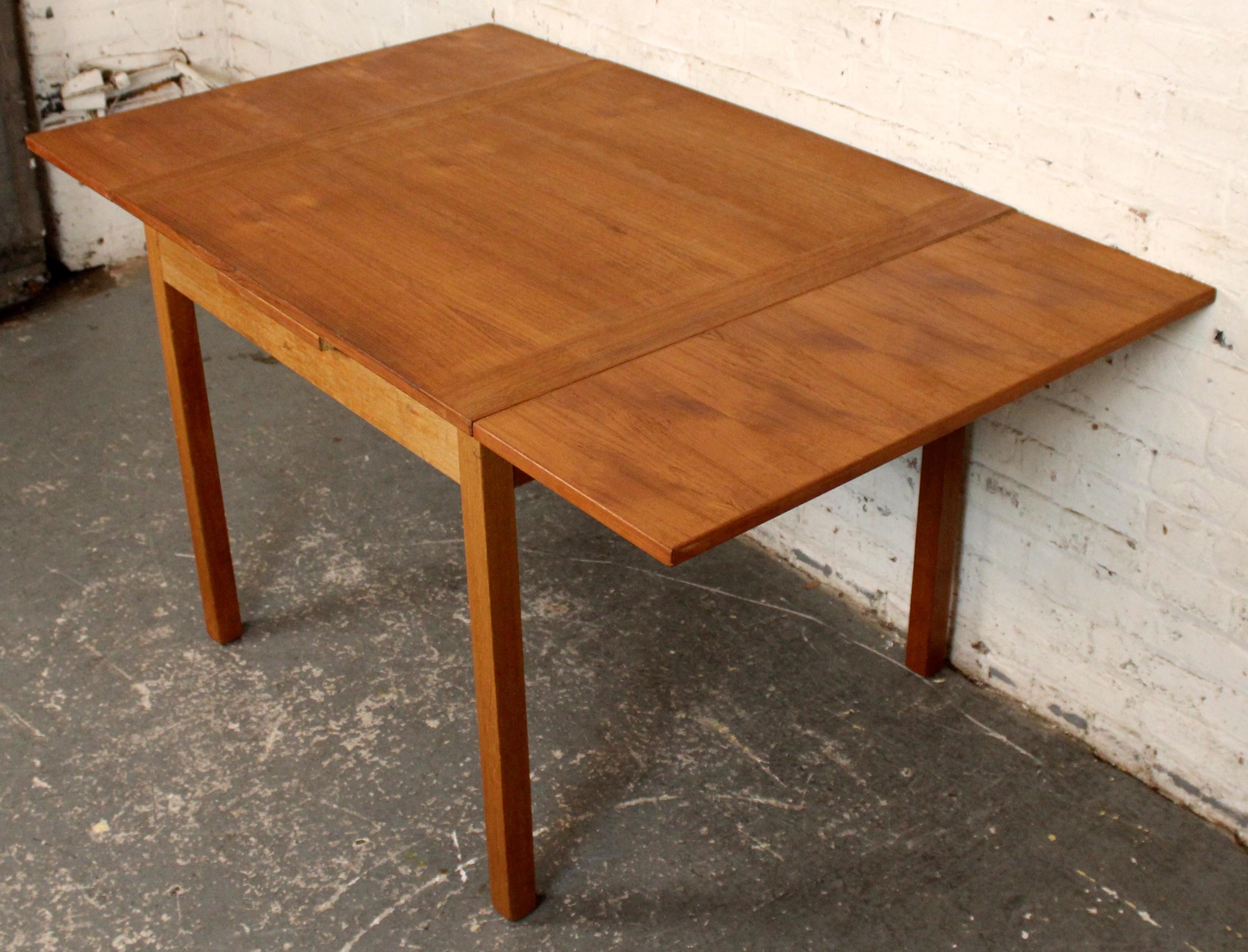 Compact Danish modern teak drop-leaf table featuring clean minimalist lines and warm, well-figured teak surfaces. The table’s dual hinged leaves fold neatly down to create a slim profile, making it ideal for small interiors or multifunctional