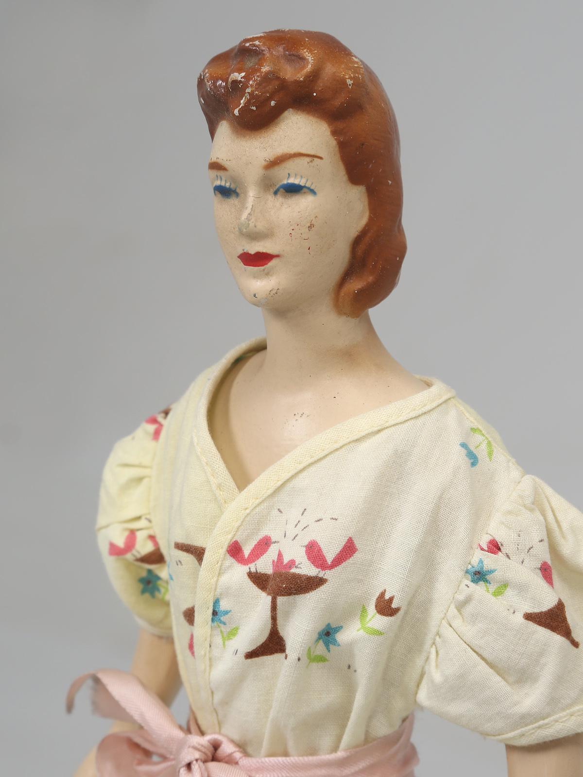 In the 1940s seeing a miniature mannequin in a department store would be common place. These would have been placed on the counters, so you could see what the available dresses would look like. Our guess is that this is probably late 1940s and is