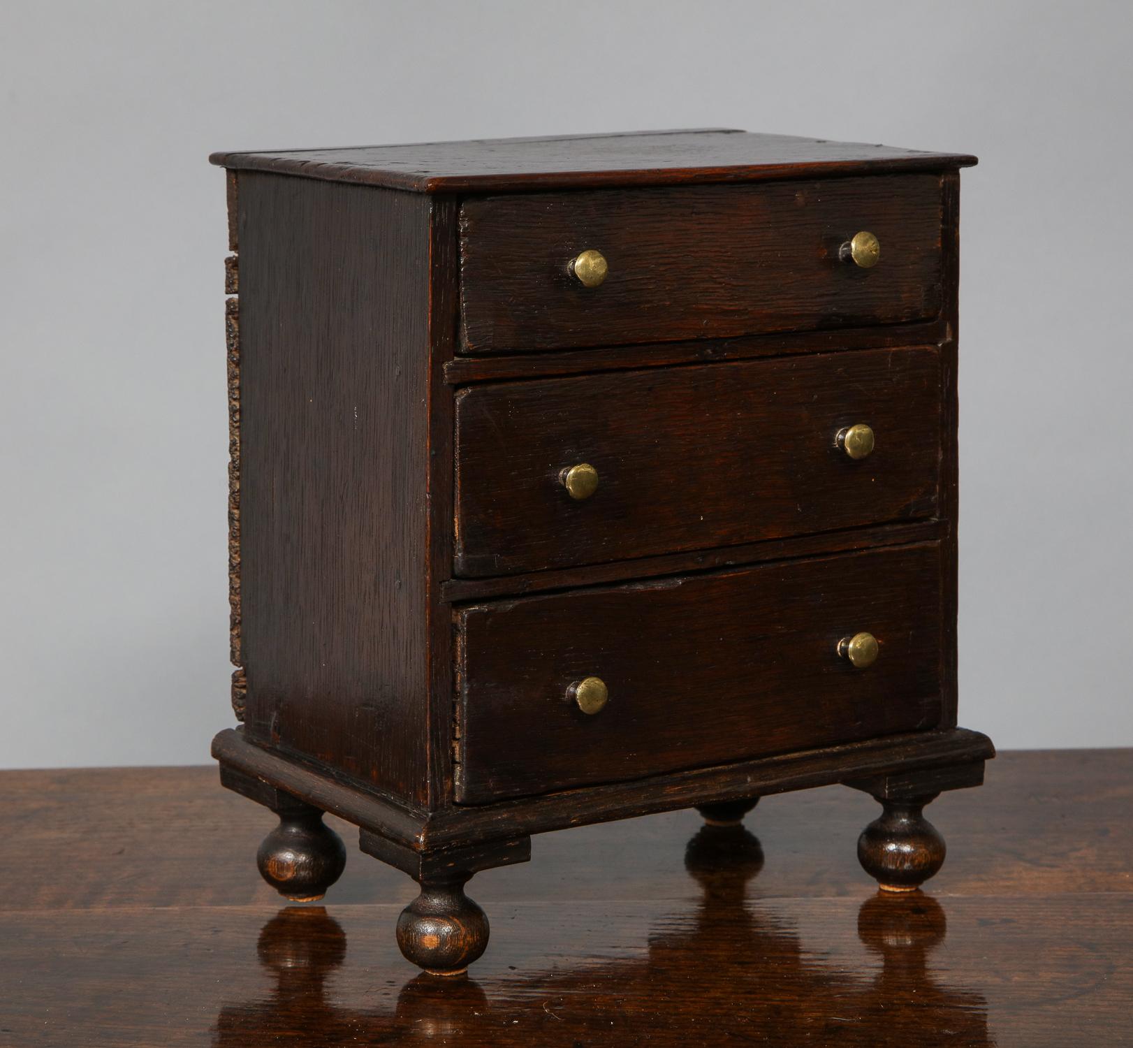 18th century English or Welsh oak chest of drawers having molded top over three drawers with brass button pulls, standing on (later) turned bun feet, the whole possessing good rich color.