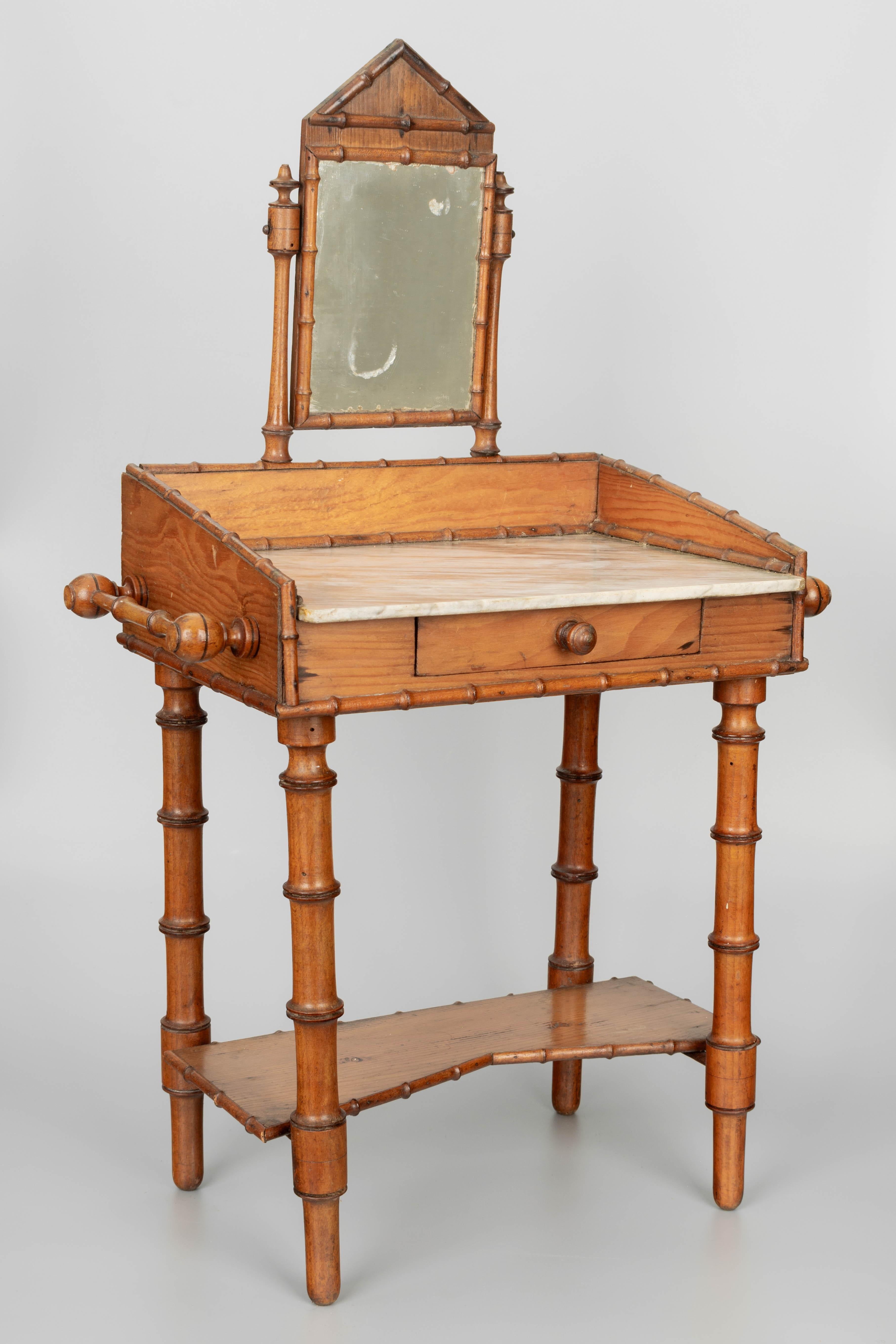 A late 19th century French miniature faux bamboo marble top doll furniture wash stand with pivoting vanity mirror. Made of pitch pine and cherry wood with a small drawer, towel bars on the sides and a shelf below. Circa 1890-1920.
Overall dimensions