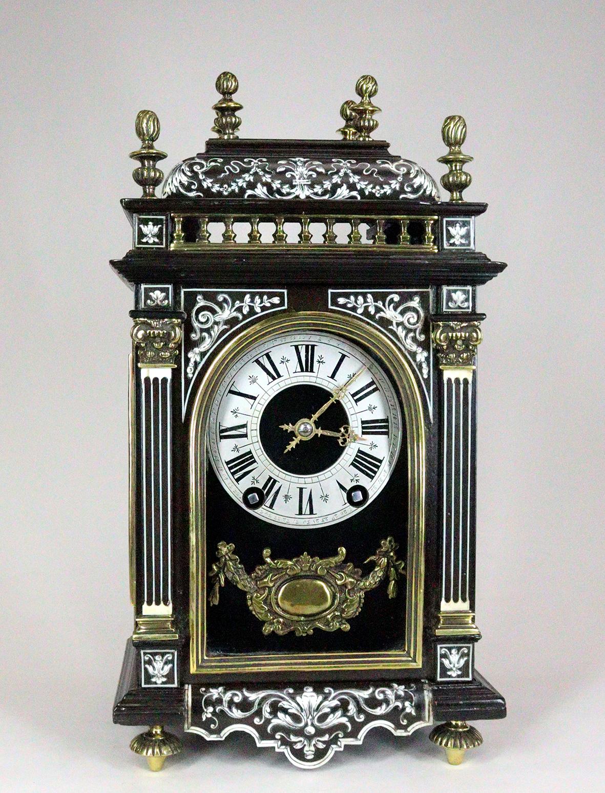Miniature Ebonised Religieuse or Bracket Clock originally sold by Dent. With engraved bone inlay, brass finials and balustrading. In the manner of a 17th century baroque clock with brass chapter ring striking on a gong.

This clock has exquisite