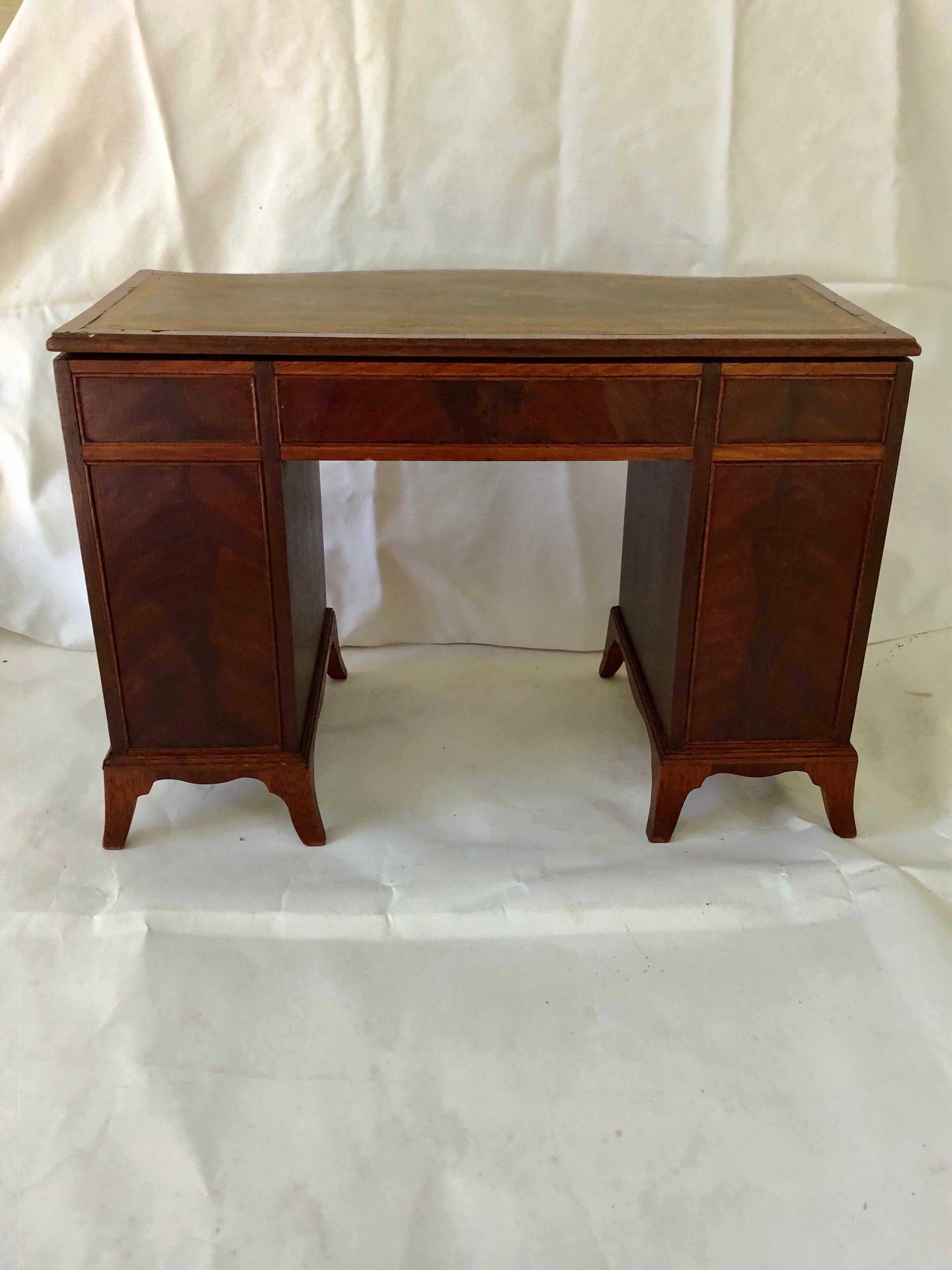 Meticulously made miniature George III style kneehole desk. Fitted with a gold tooled green leather top, central frieze drawer flanked by four short drawers in each
pedestal. Total of 9 working drawers. Finished back. Leather fitted top can be