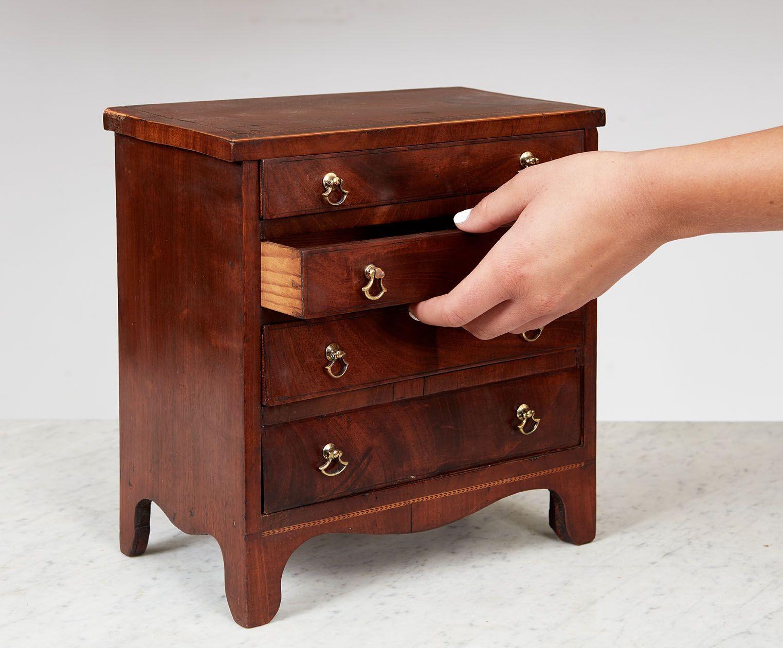 Fine George III mahogany miniature chest of drawers having string inlay and cross banded top, the drawers with original axe-head pulls retaining traces of fire gilding, standing on simple shaped bracket feet.  English, circa 1780.