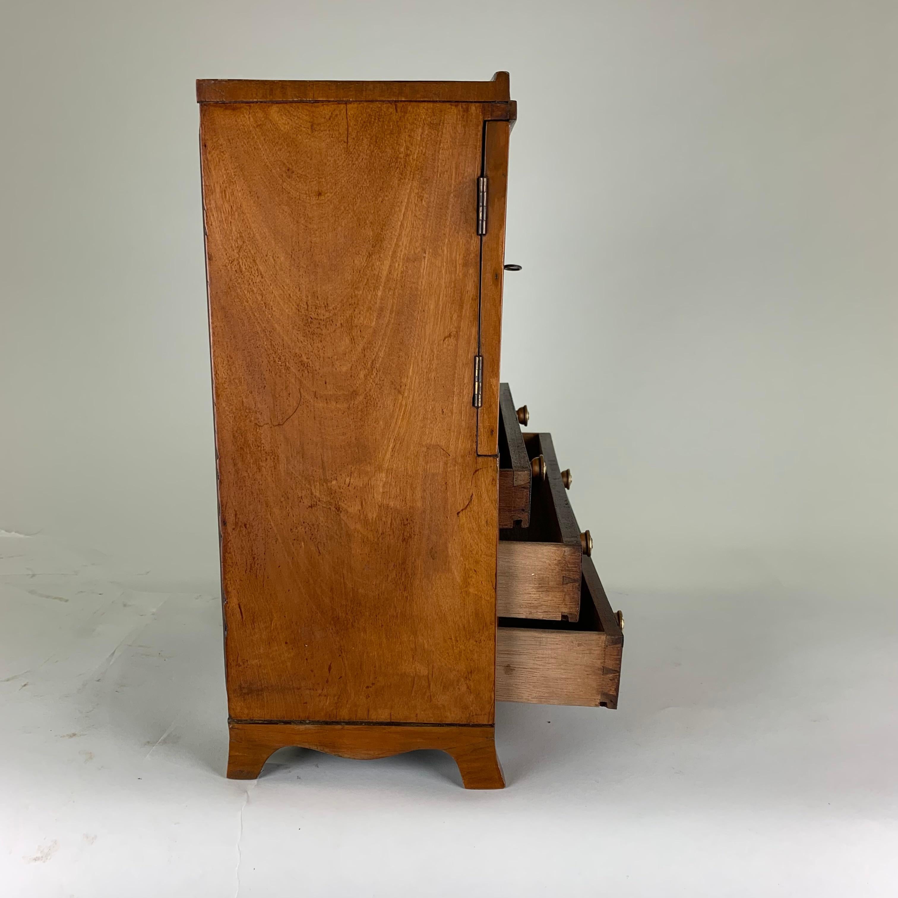 An exceptionally fine quality and rare Regency, miniature satinwood linen press on splay feet with a shaped apron. Fitted with three long drawers with brass knobs. The top has a pair of doors with oval panels enclosing three sliding trays.
A