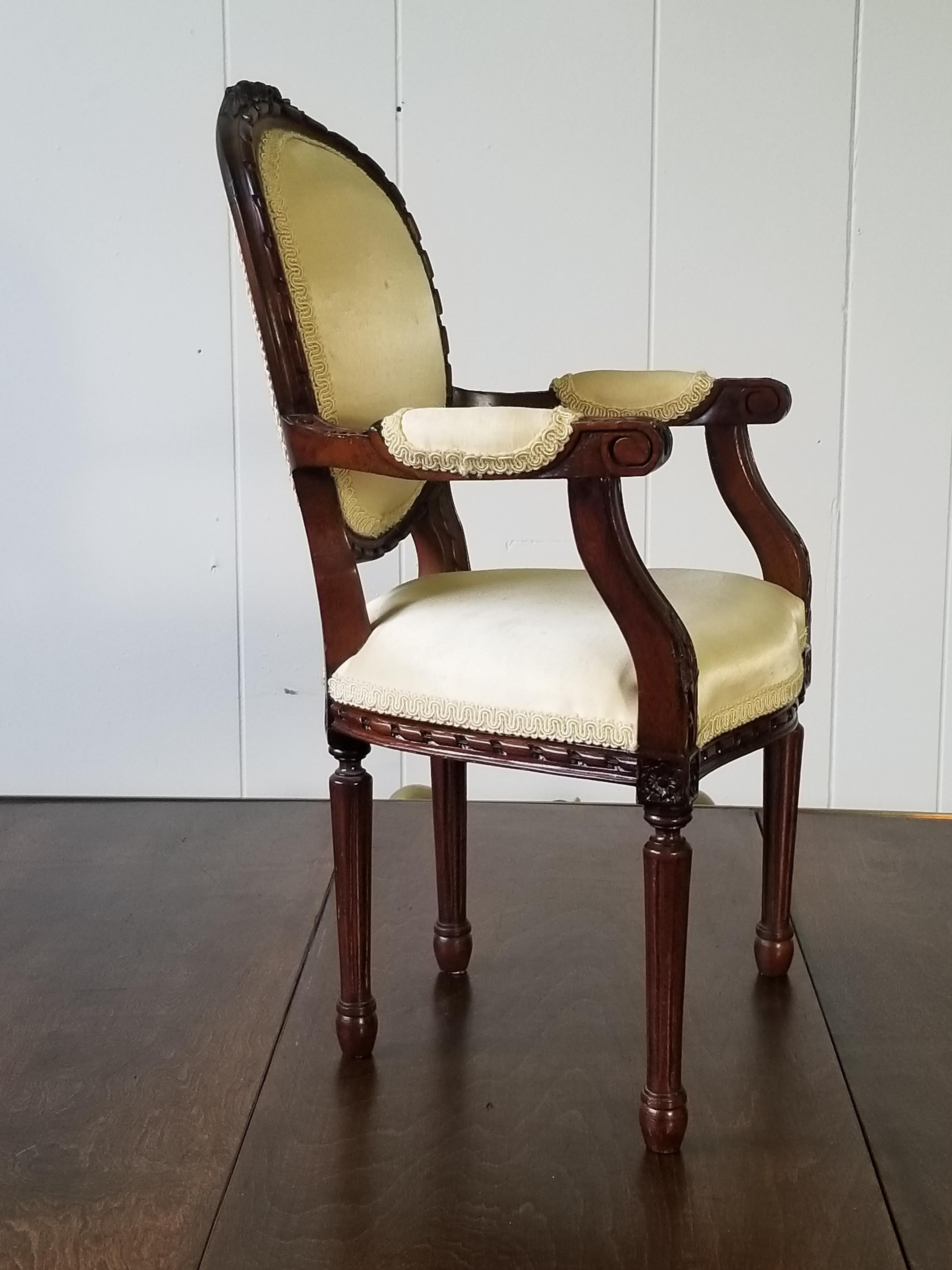 antike Reproduktion eines Miniatur-Fauteuils aus dem 20. Jahrhundert im französischen Louis-XVI-Stil. Der Sessel hat eine ovale Rückenlehne mit geschnitzten Bändern und einem Bogenknoten am Scheitel. Die Arme sind bis zu geschnitzten Rosetten und