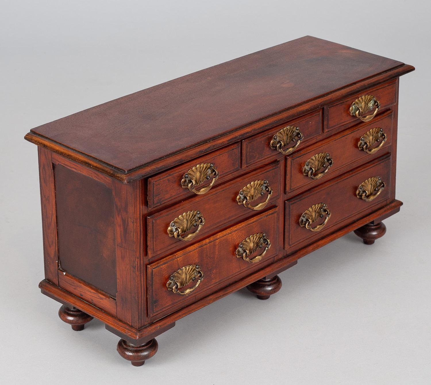 Miniature mahogany chest of drawers with two short drawers over two rows of two drawers each, brass shell-shaped back plates with bail handles, raise on turnip shaped feet.