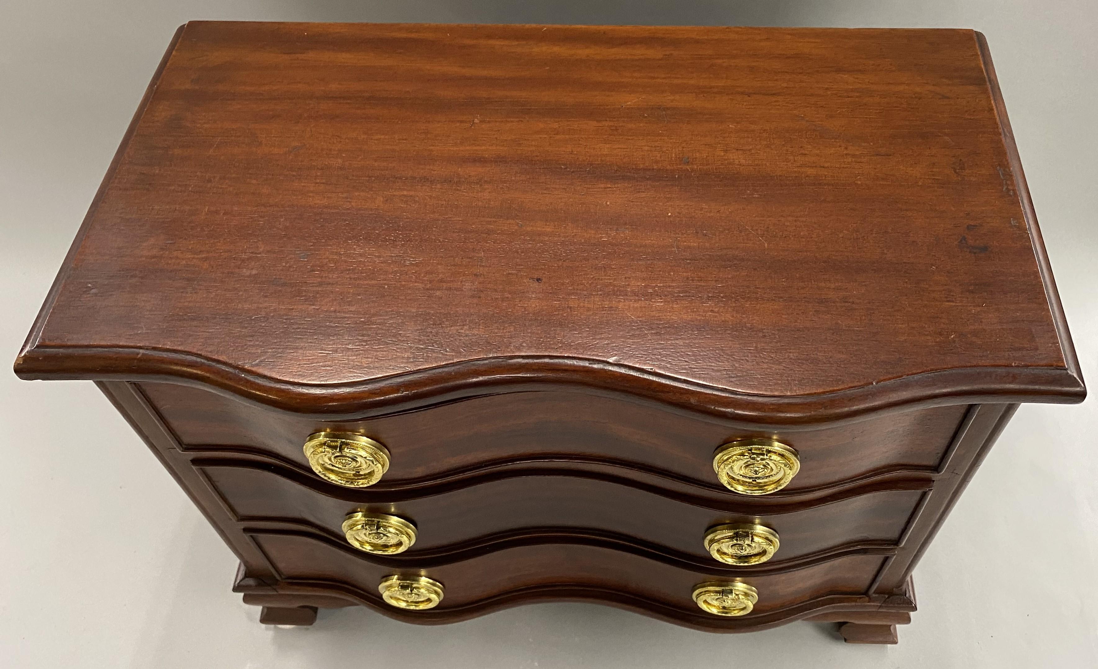A fine miniature mahogany serpentine three drawer chest in the Chippendale style with molded conforming top edge, round brass pulls and carved ogee feet. Would make a great jewelry chest. Dates to the 20th century in very good condition, with some