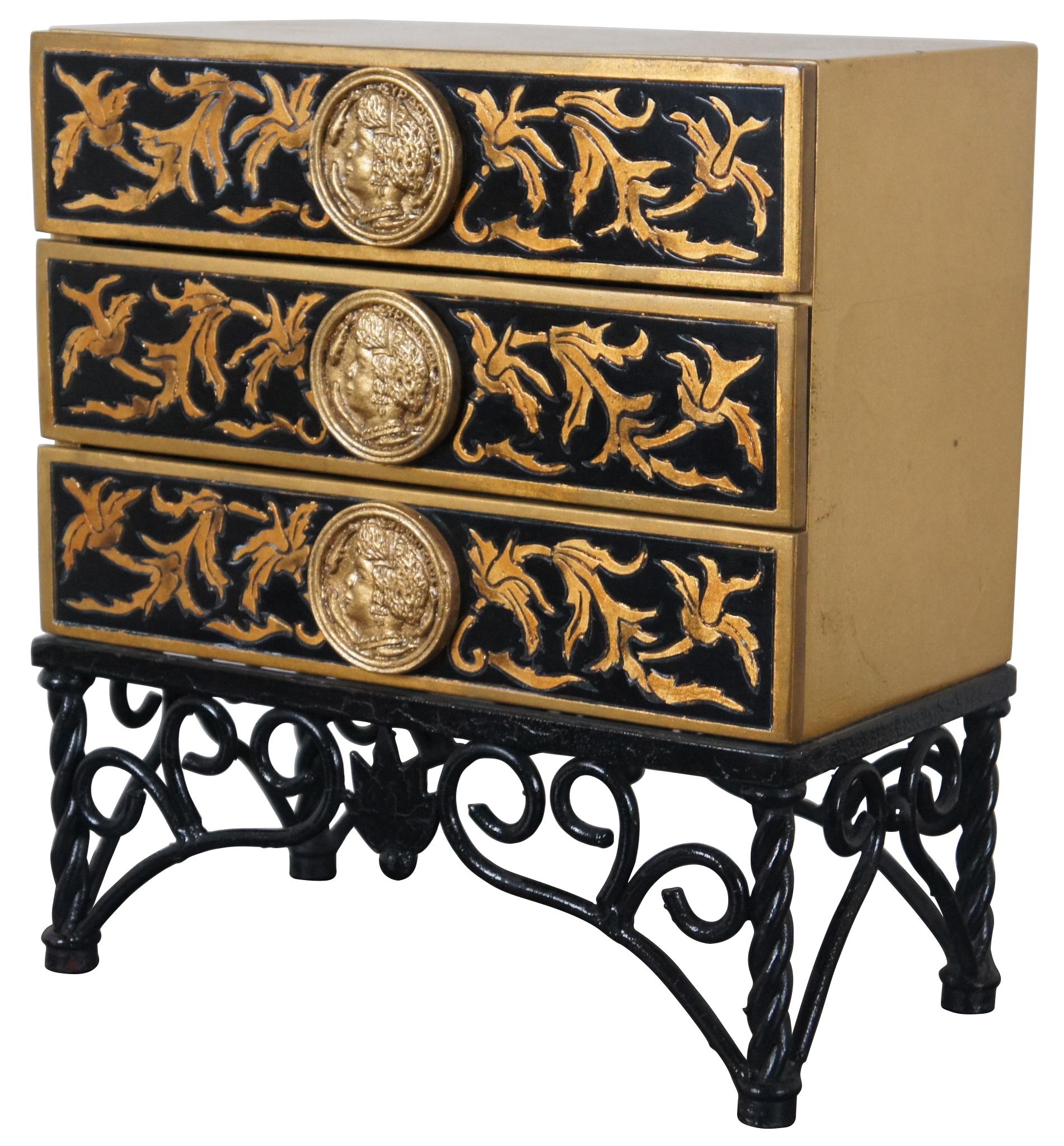 Three drawer table top jewelry box or storage chest. Neoclassical or Napoleonic style with gold and black lacquered drawers, mounted with medallions shaped like antique coins, mounted on a black wrought iron base.
  