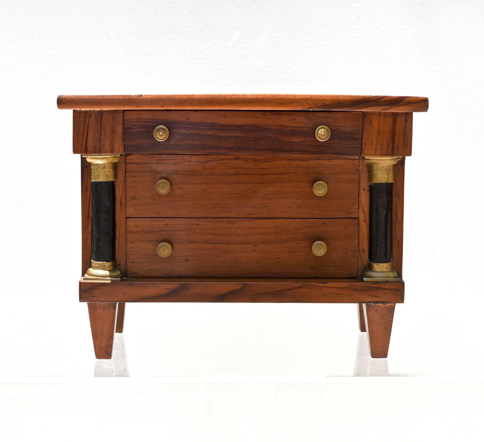 Italian neoclassical tabletop commode of fruitwood. The simple top rest upon three paper lined drawers, flanked by ebonized inset columns and terminates on gently tapering feet. The petite chest of drawers will make for stylish storage of everyday