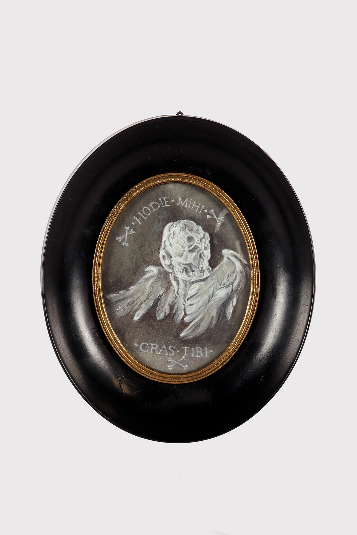 Miniature depicting a Memento Mori painted in gouache on paper, grisaille technique. The frame, in ebonized fruitwood and finished with wax, black in color, is oval in shape with an oval inside bordered by a gold-plated brass decoration that fixes
