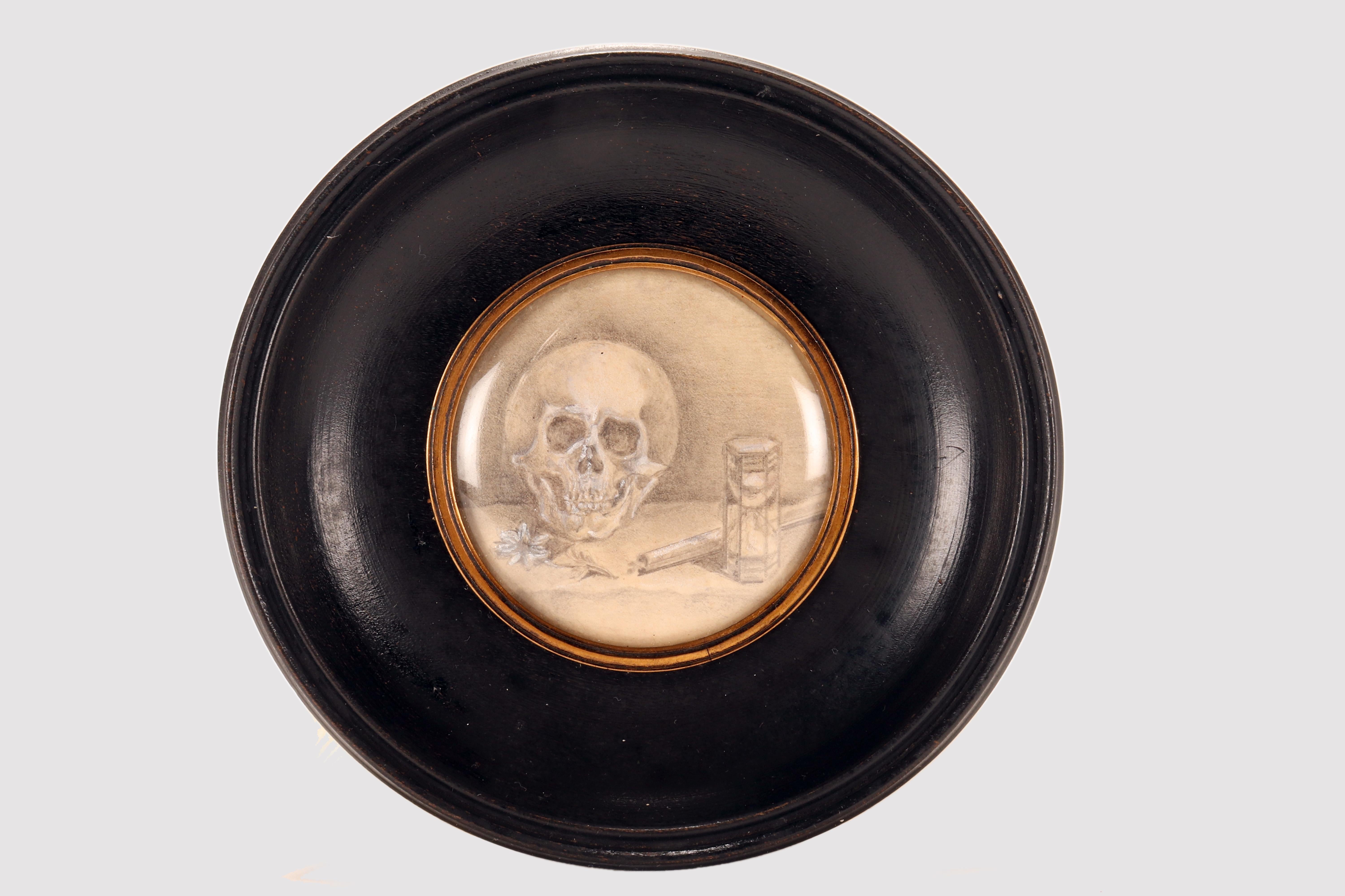 Miniatur einer Vanitas Memento Mori, gemalt mit Bleistift auf Papier. Der Rahmen aus ebonisiertem Fruchtholz, der mit schwarzem Wachs bearbeitet wurde, ist rund mit einem Kreis im Inneren, der von einer vergoldeten Messingverzierung eingefasst wird,