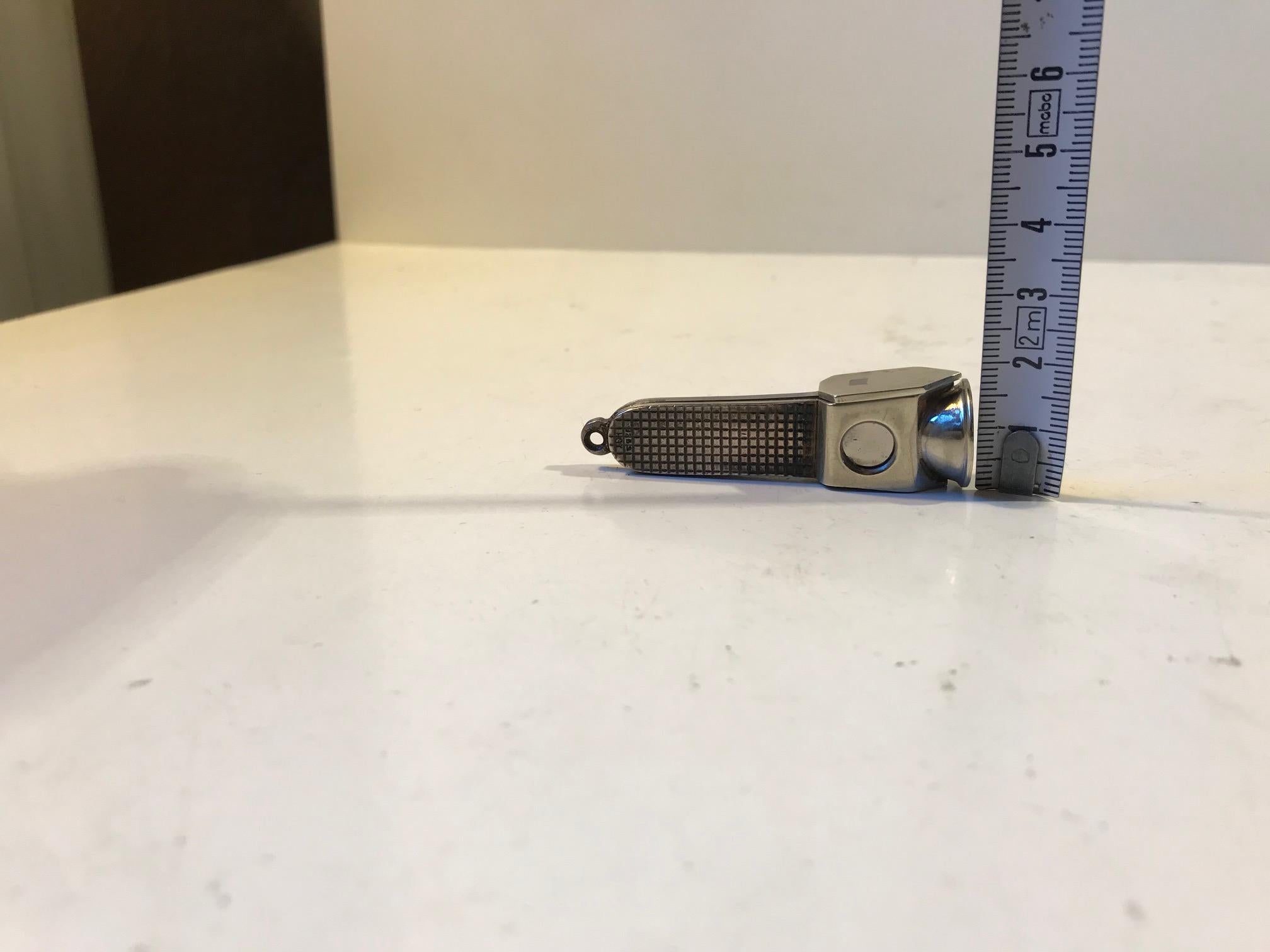 Measuring 55mm in length and 18mm in height this small cigar cutter can be used as a keychain pendant or hidden away in your package of cigars. The handle is made from 925s silver set in a petite square pattern. It is hallmarked 925s and has the