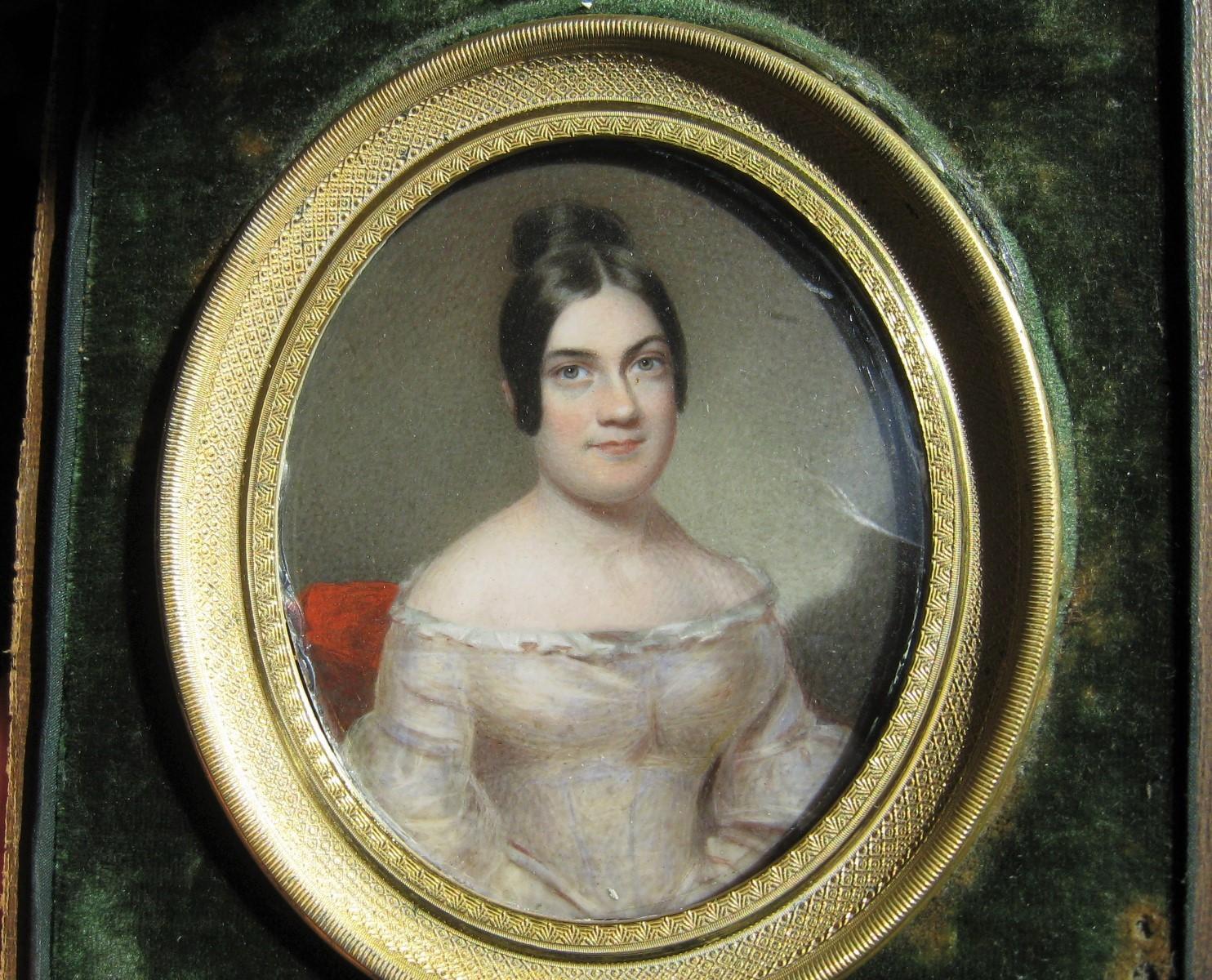 Miniature portrait painting of a lovely young woman, circa 1840. Brown leather travel case with green velvet lining. Gilt bronze interior frame surrounds the portrait. Glass covered. Leather case measures about 5.5