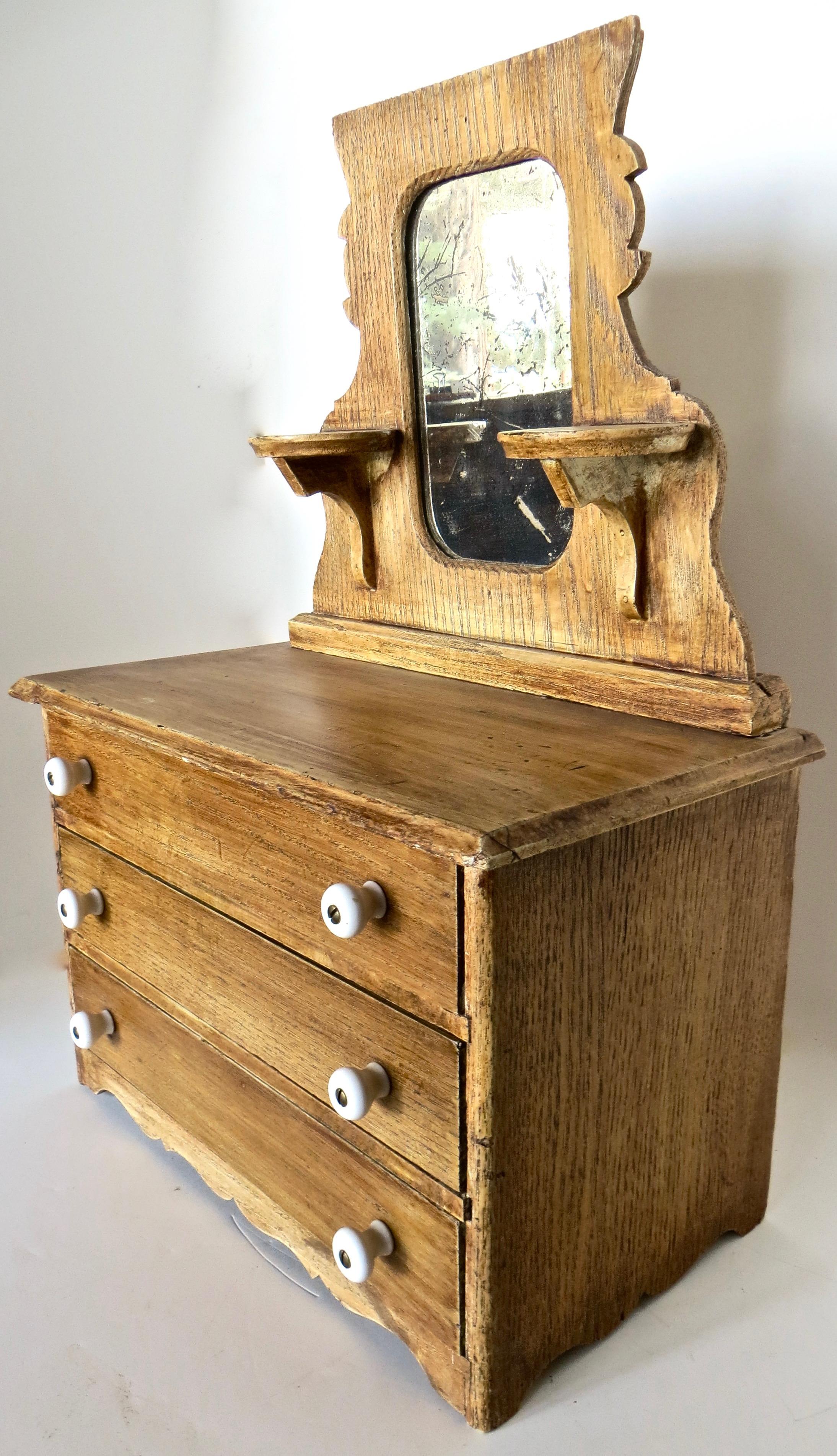 This late 19th century miniature 3-drawer dresser with original mirror mounted above, was likely used as a salesman's sample by an itinerant sales person who traveled the countryside promoting his articles, usually by seeking out merchants to take