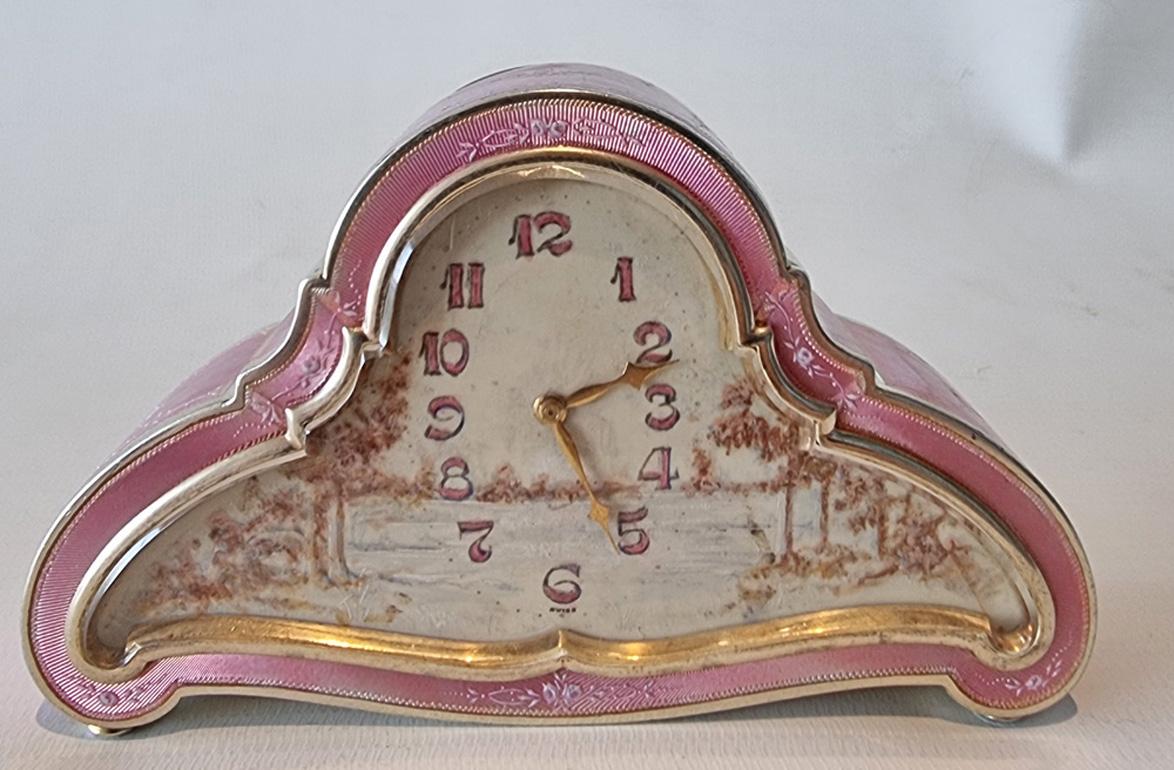 A superb silver gilt and pink guilloche enamel carriage or boudoir clock with overpainted swags of flowers. Superb engine turned design is highlighted over the hand painted swags of flowers. Unusual case design, this clock with a hand painted scene
