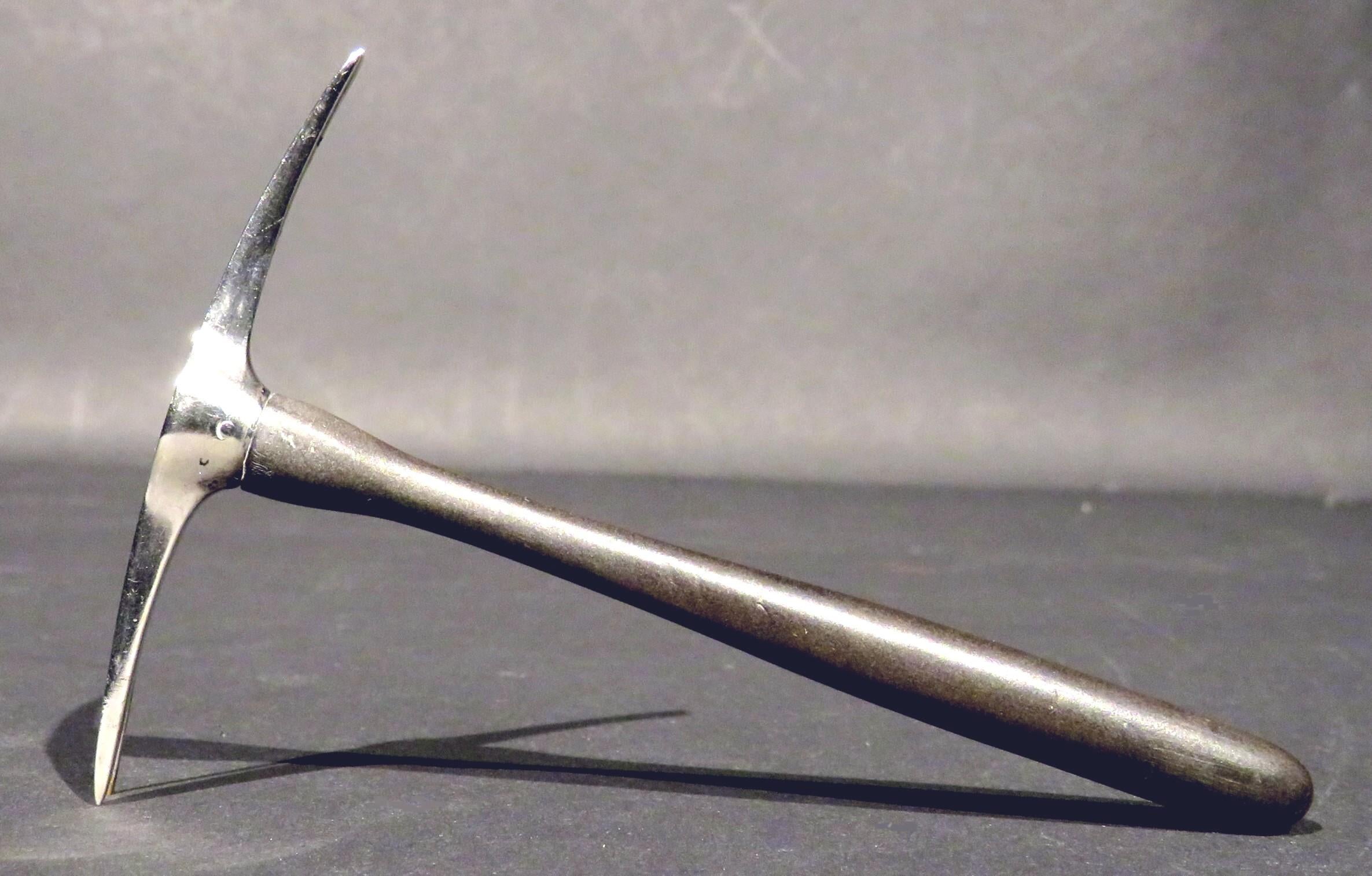 A most intriguing and relatively rare miniature model of a sterling silver pickaxe, showing a sterling silver axe-head affixed to a finely turned ebony handle. The sterling axe-head bearing impressed makers mark for Rogers, Lunt & Bowlen Co.,