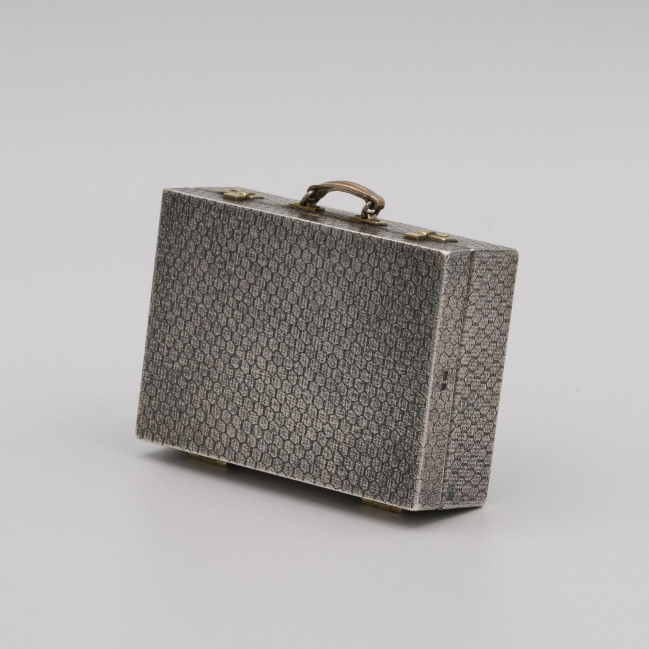 A fantastic miniature sterling silver and gold suitcase by renowned jeweler and miniaturist Karel Bartosik, hallmarked London 1983. Incredible detail; It has a snakeskin decorative finish to the outside of the case, hinges and mock catches made of
