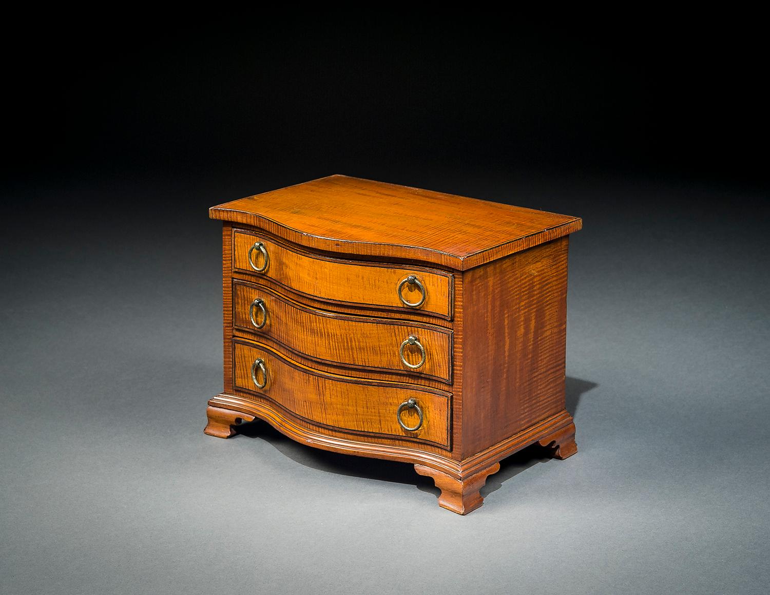 American, probably Boston or Salem, Massachusetts
Miniature Serpentine Chest of Drawers, circa 1785-1800
Striped maple, ebony, and rosewood (secondary woods: mahogany), with brass drawer pulls
Measures: 7 7/8 in. high, 10 1/2 in. wide, 7 3/16 in.