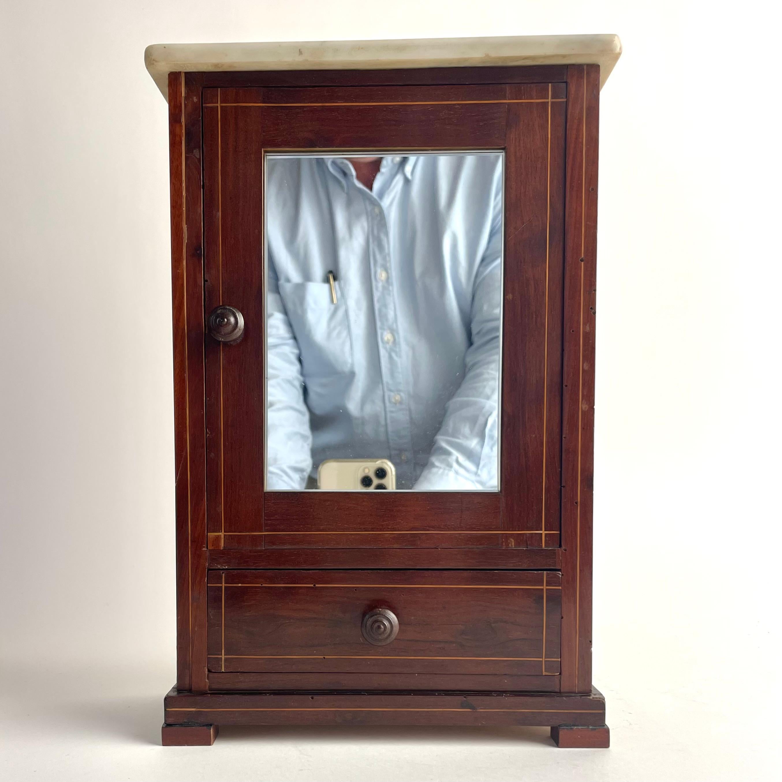 Meuble miniature en noyer avec plateau en marbre de Carrare, France, XIXe siècle

Charmante armoire miniature en noyer, finement travaillée, aux lignes délicates et incrustées, avec une porte en miroir au-dessus d'un tiroir unique. Le meuble est