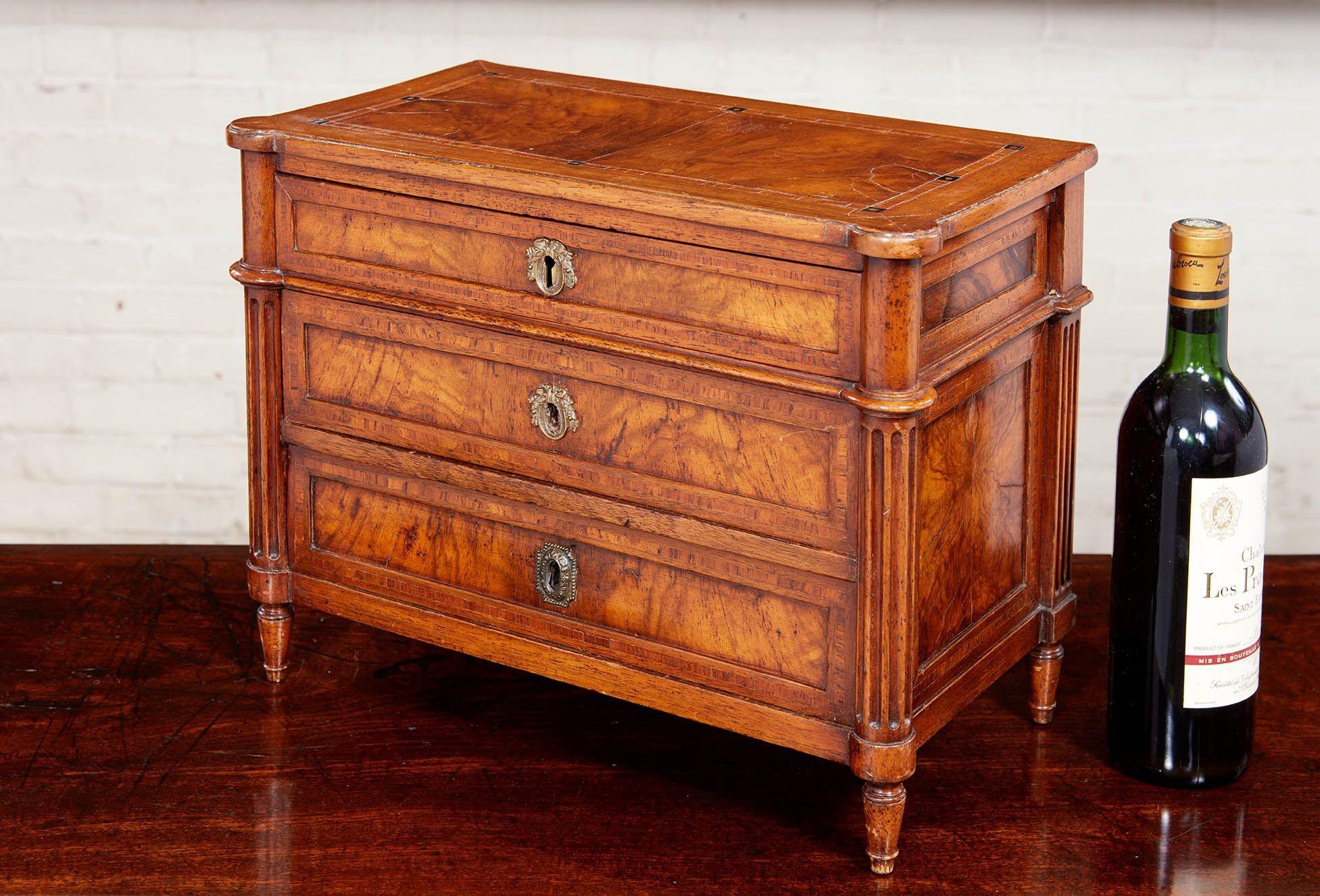 Early 19th Century walnut commode, the inlaid top with cookie corners over turned and fluted legs flanking three inlaid drawers and standing on turned turnip feet, French or Italian circa 1800.