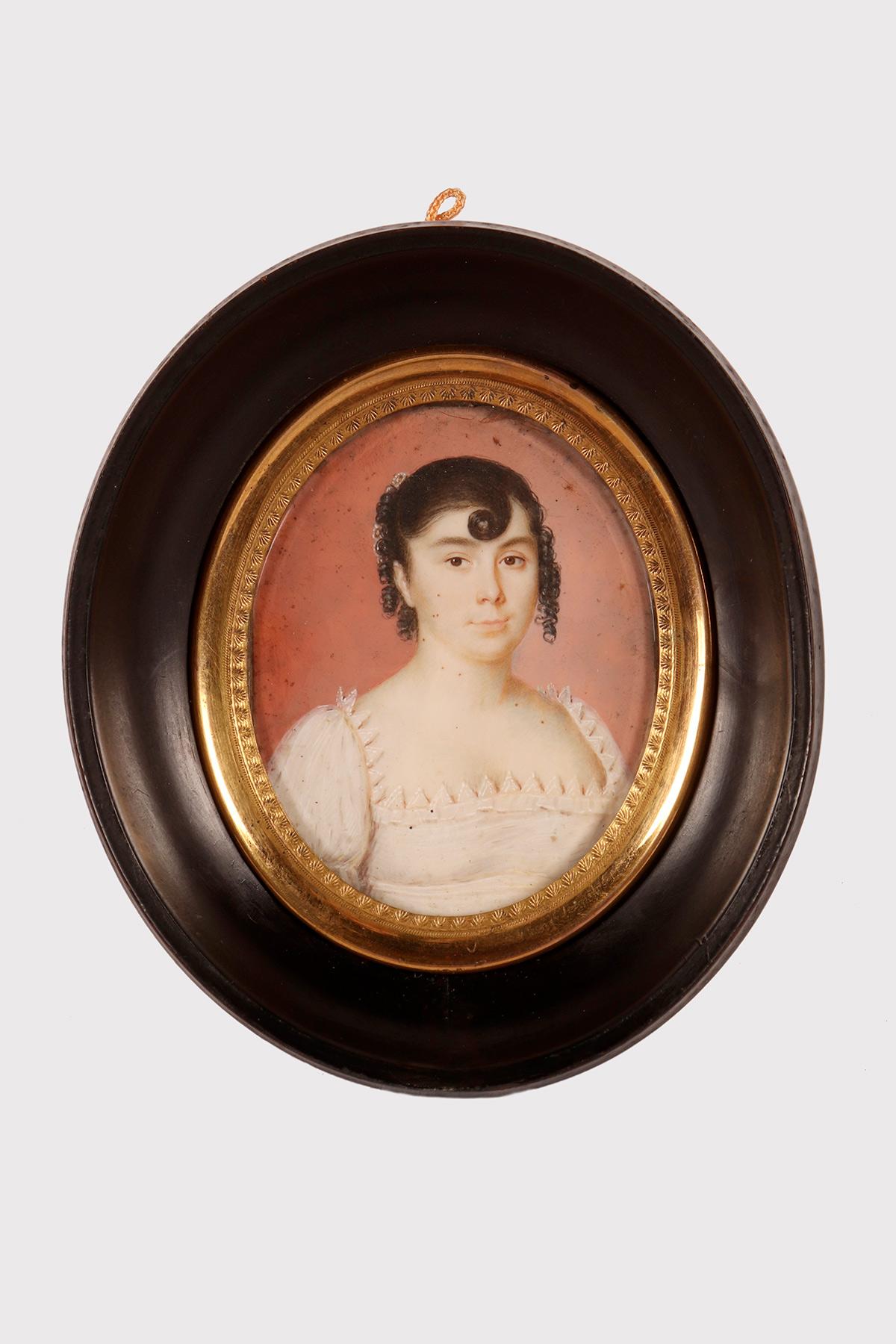 Miniature avec sujet féminin, aquarelle sur ivoire.
Le cadre, en bois fruitier ciré de couleur noire, est de forme ovale. L'intérieur de l'ovale est délimité par un cadre décoré en laiton doré qui fixe le verre.
La miniature représente un personnage
