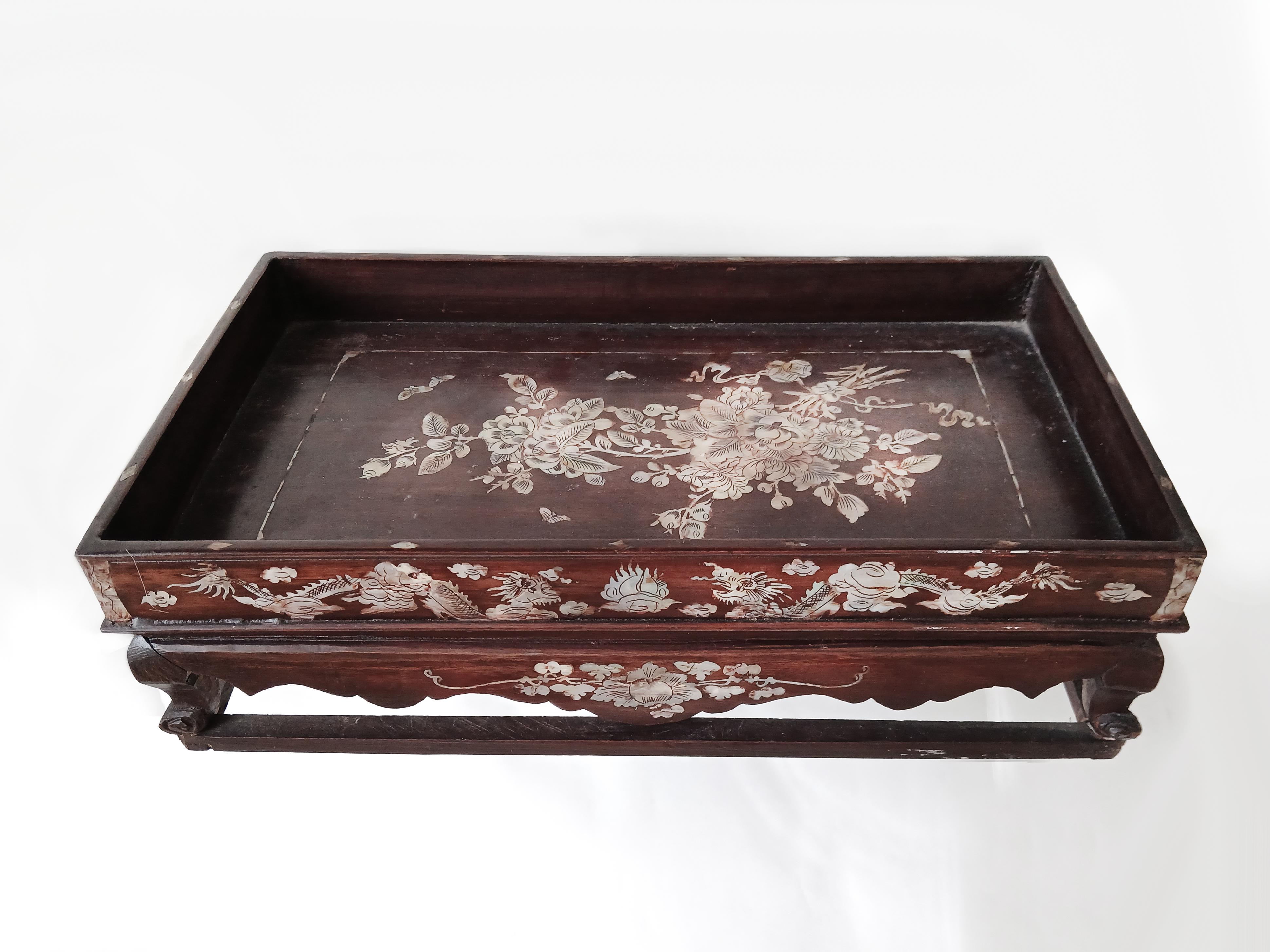 A small altar tray, hand-crafted in teak with mother-of-pearl inlays. China, late 19th Century.  

Rustic teak in a dark brown/red semi-gloss finish. Four stretchers connect the turned legs. Delicate mother-of-pearl inlaid decorations throughout,