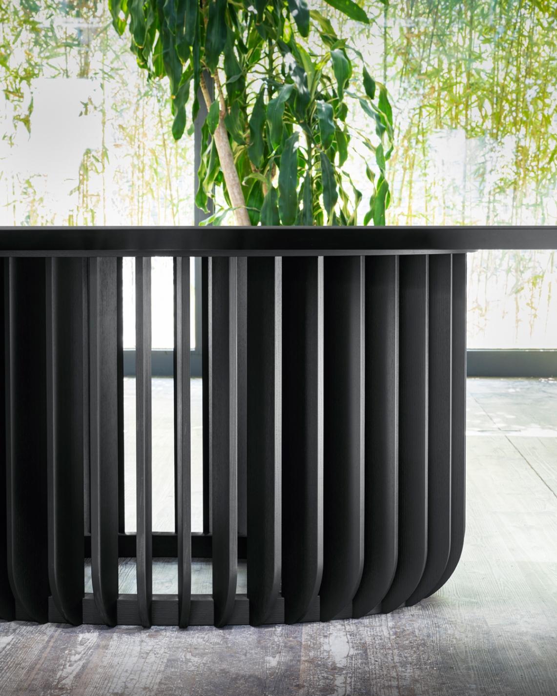 Juice is a monumental table with a meditative air. Its essence lies in the base, where the long wooden legs attach to a ring, encircling it. Juice, a table developed around the balance between filled and empty spaces, creates a sensation of perfect