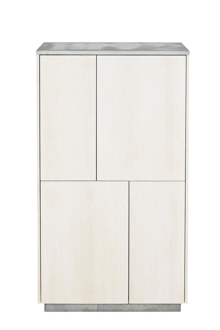 This 4 door armoire features clean and simple lines. The exterior is composed of white stained rift-cut white oak with an oil finish. The top and base are cast-concrete while the insides reveal a burst of mint-green color. The doors are Blum