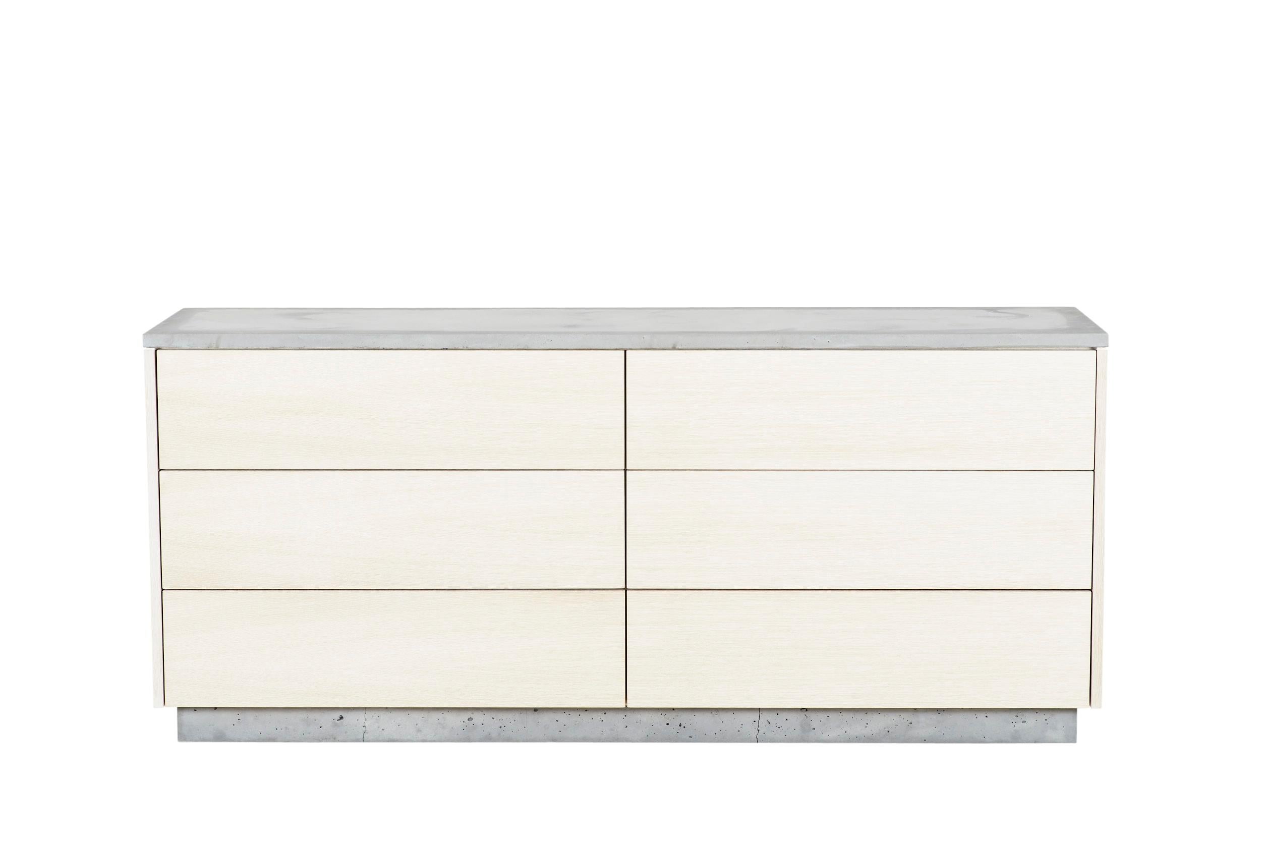 This 6-drawer dresser features clean and simple lines. The exterior is composed of white stained rift-cut white oak with an oil finish. The counter top and base are cast-concrete while the insides reveal a burst of color with mint-green drawers. The