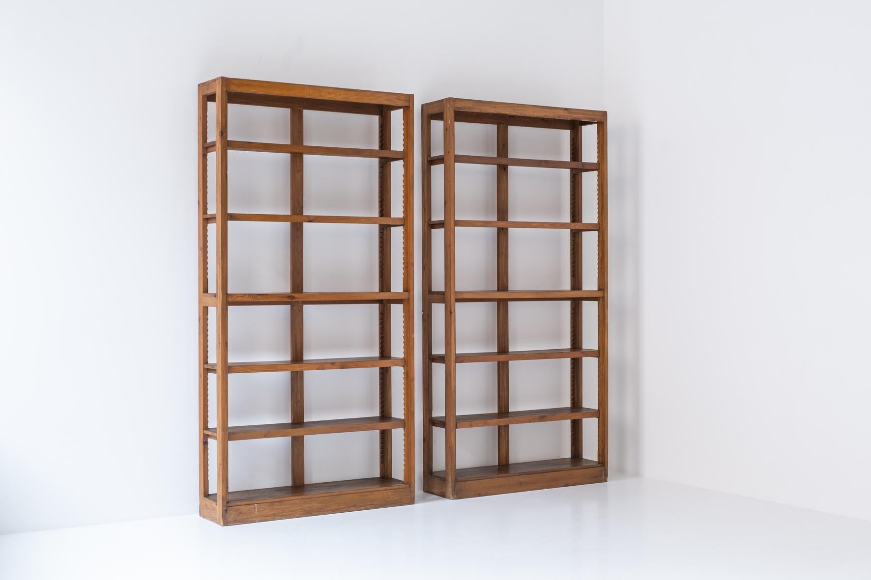 Great pair of minimal bookcases in solid elm from France, designed and produced in the 1950s. This identical pair features series of adjustable shelves and is presented in its original condition with some visible wear from age and use. Due to its
